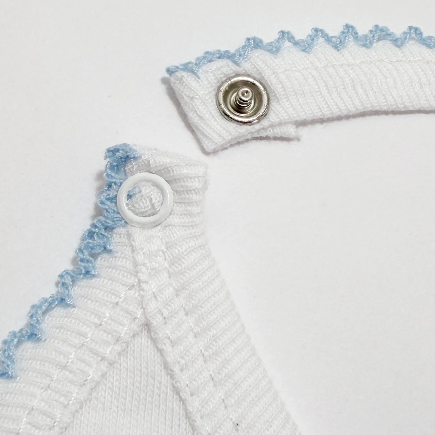 Detalle de babero con motivo de conejitos abrazados azul