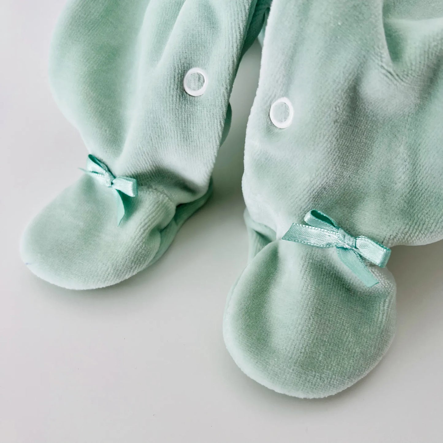 Detalle de pelele de niño con bordado de rombos verde