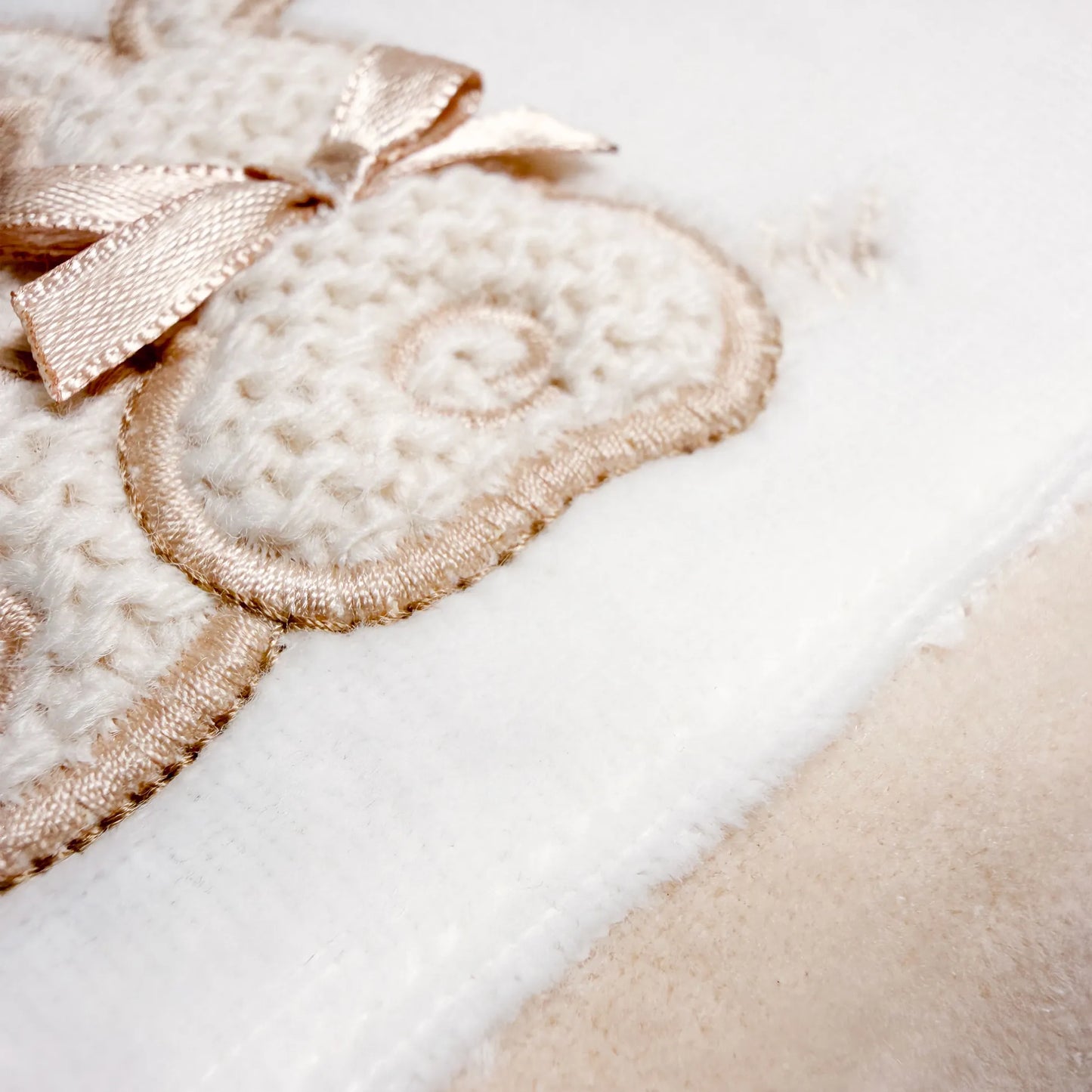 Detalle de pelele con motivo de conejos de punto y lazito beige