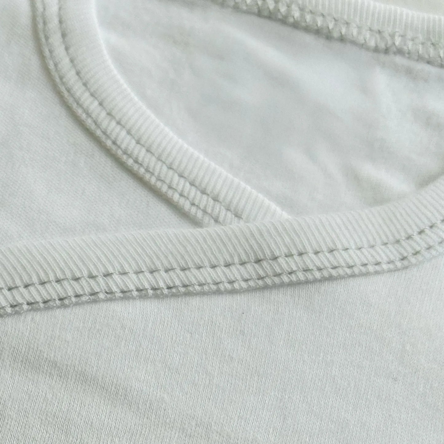 Detalle de body cruzado perchado con osito bordado a punto de cruz gris