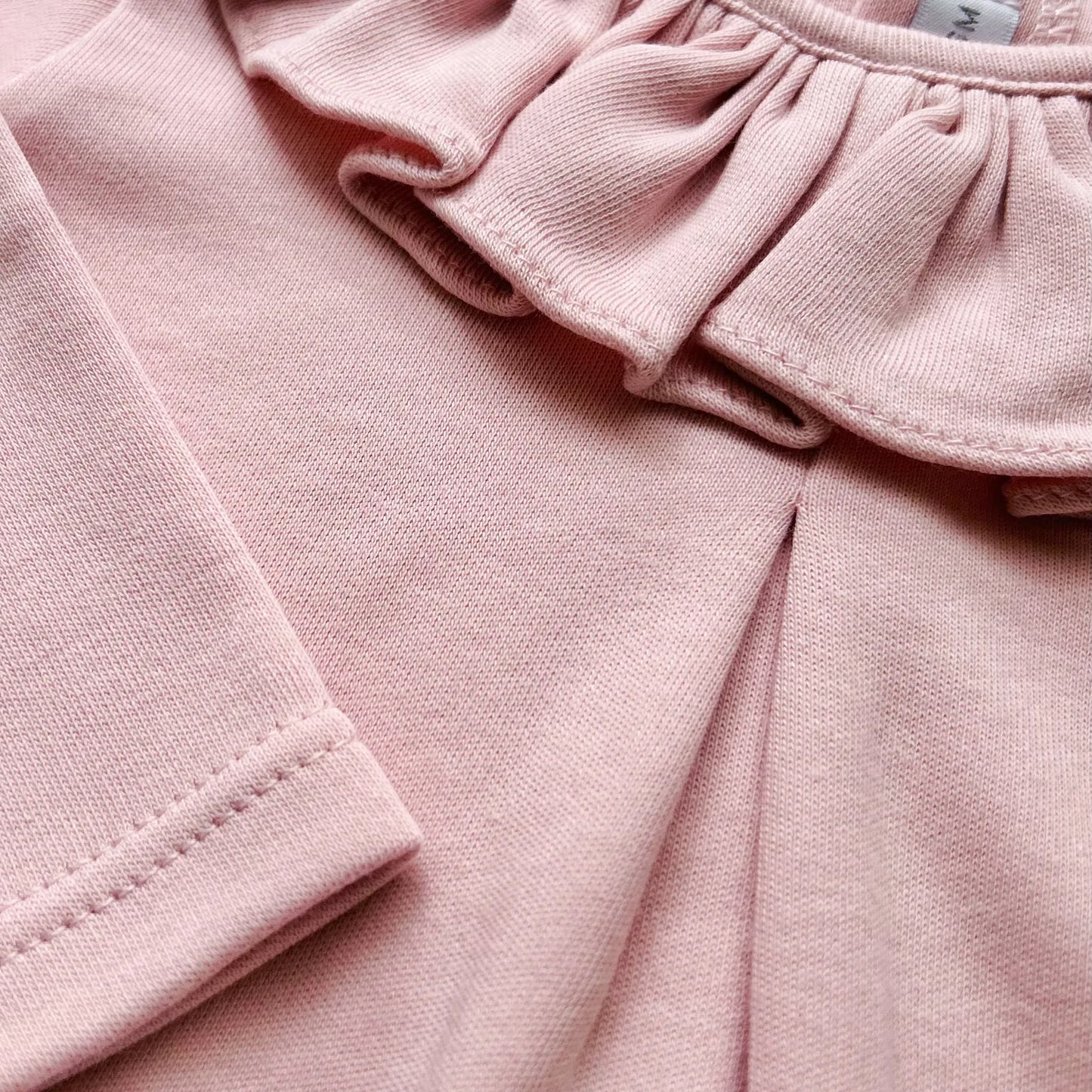 Detalle de camisa de niña con volante en el cuello y pliegue delantero rosa