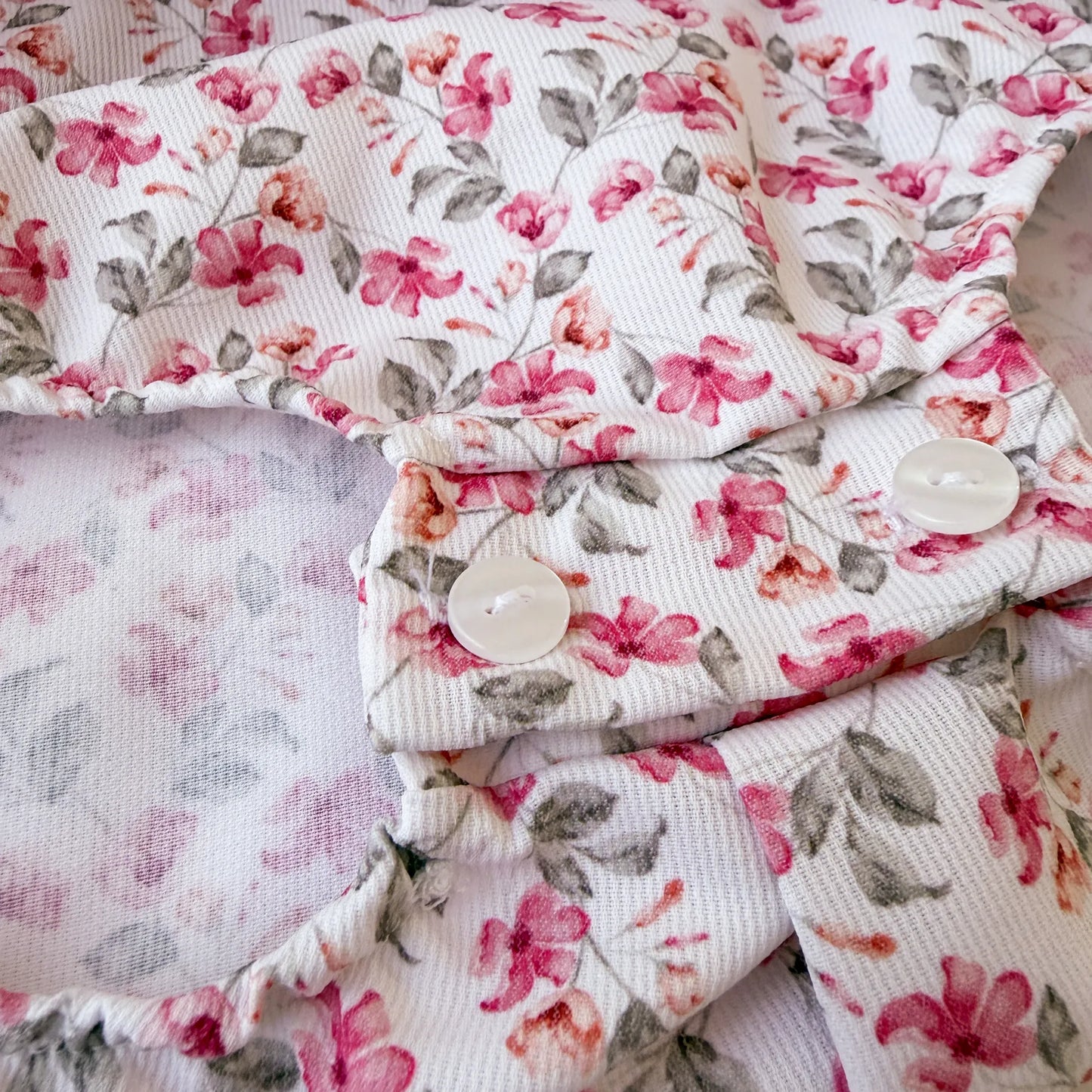 Detalle de ranita de niña de estampado floral con volante en el cuello y lazo en la frente