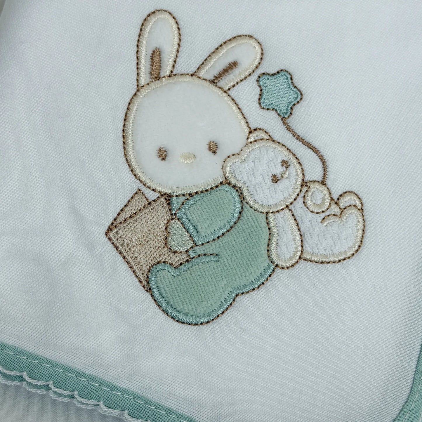 Detalle de paño para eructar con motivo de conejito y osito con libro verde