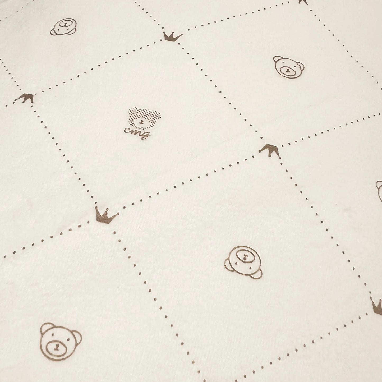 Detalle de manta de doble cara con estampado de ositos y rombos en un lado perla