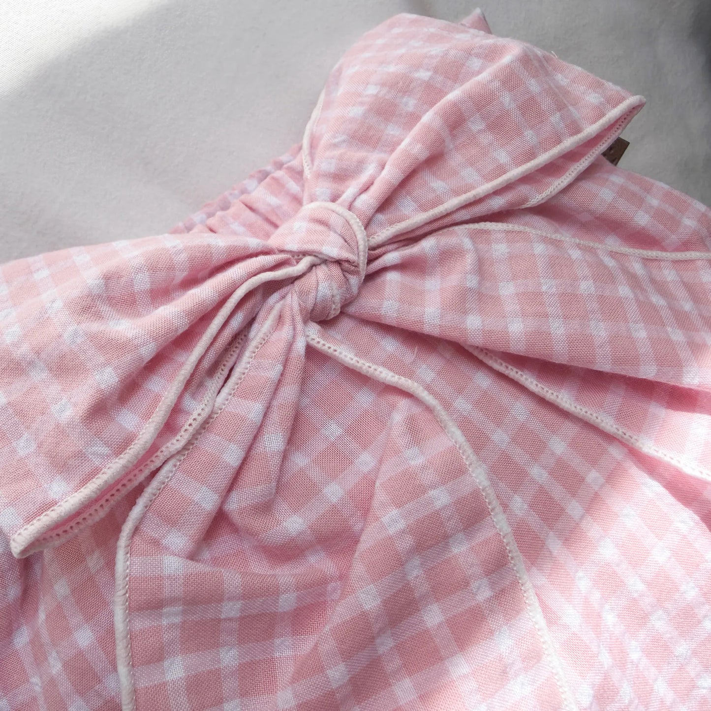 Detalle de cubrepañal de niña en tela con lazo delantero y volantes rosa
