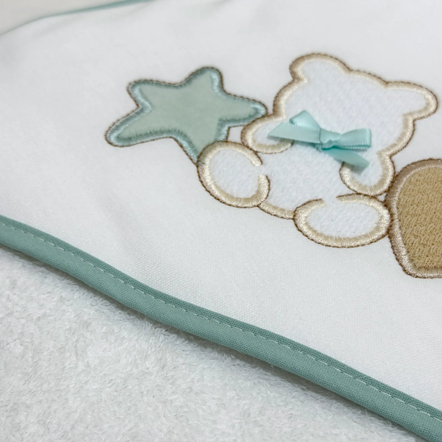 Detalle de toalla con motivo de osito entre estrella y corazón verde