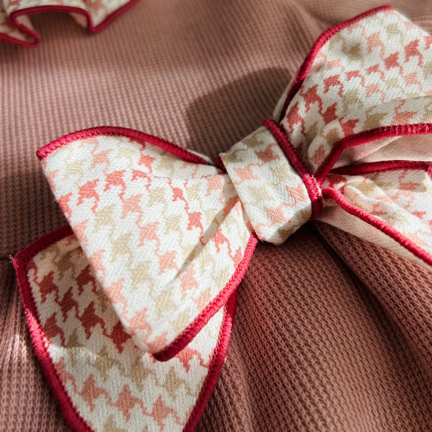 Detalle de vestido con volante en el cuello y puños y lazo en la cintura rosa