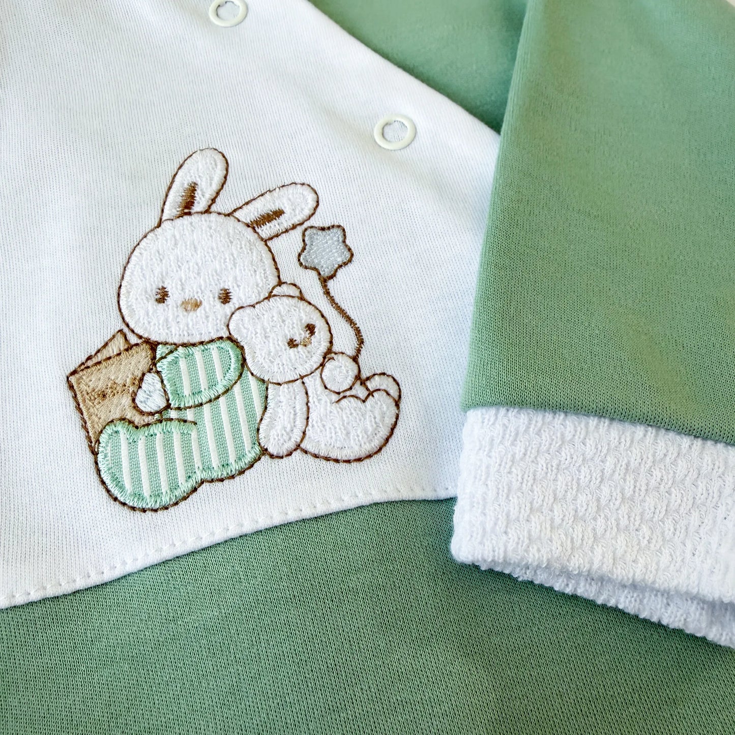 Detalle de pelele de algodón con motivo de conejito y osito con libro verde