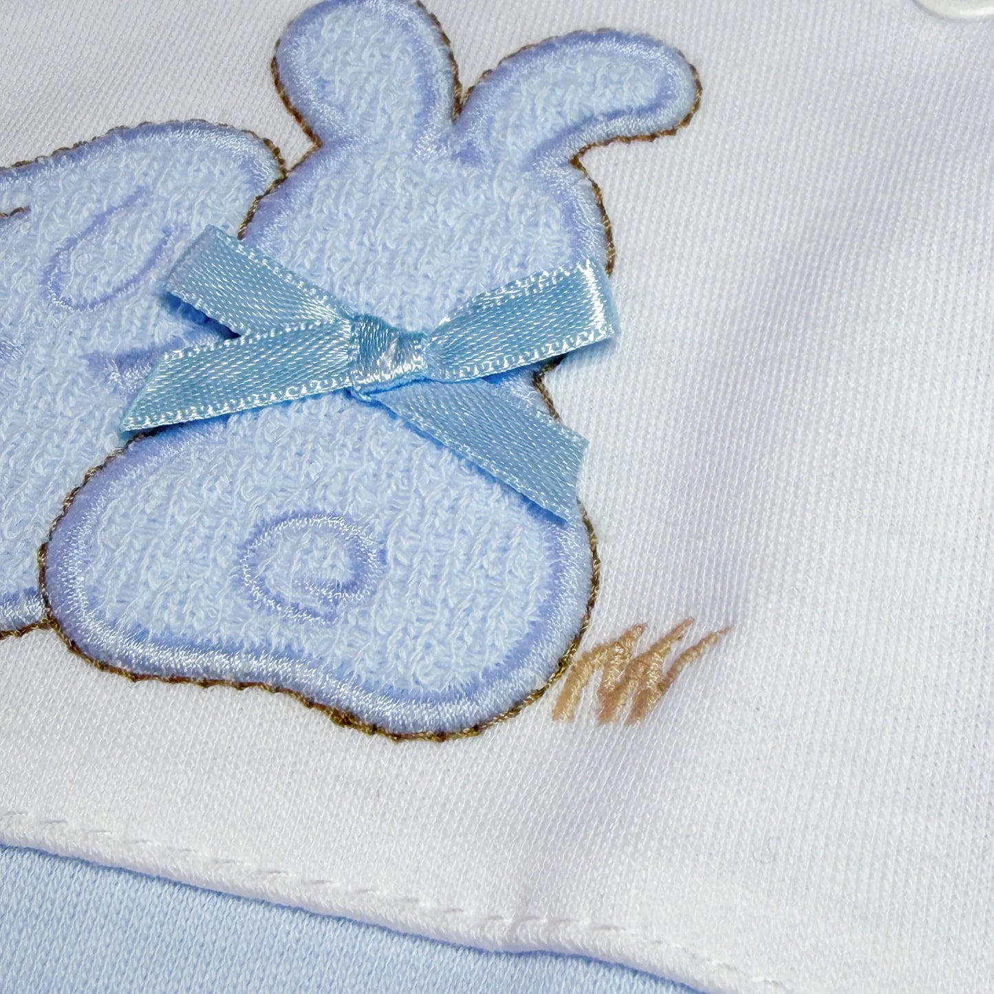 Detalle de pelele de algodón con motivo de conejos de punto y lacito azul