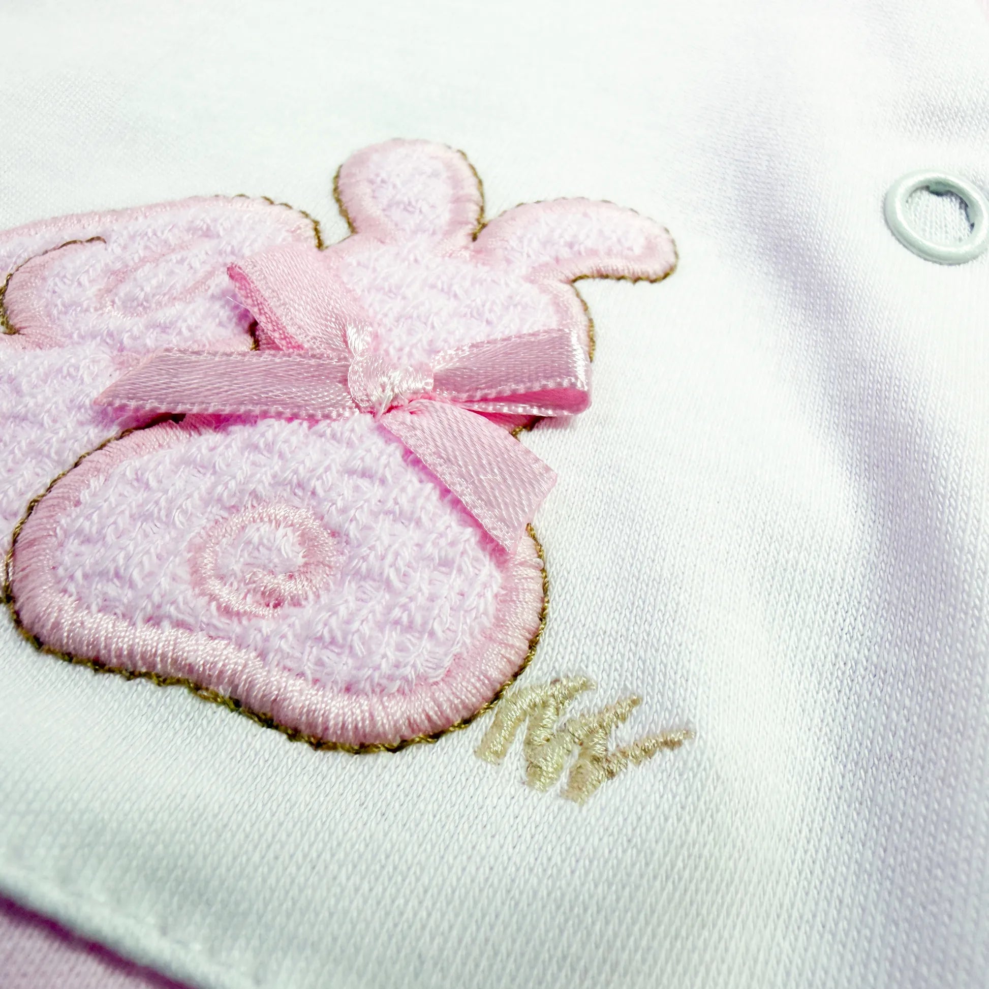 Detalle de pelele de algodón con motivo de conejos de punto y lacito rosa
