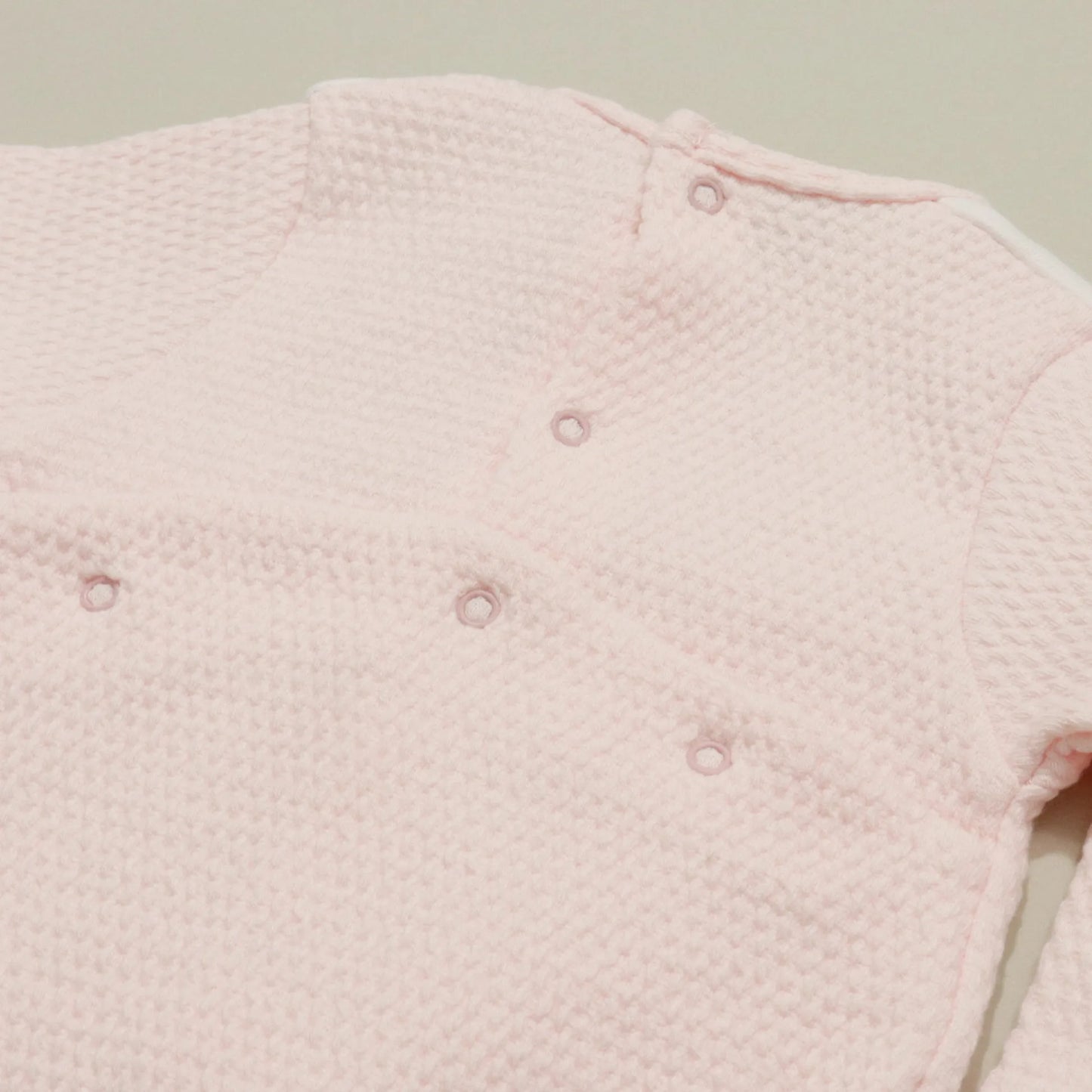 Detalle de pelele con efecto encaje y lazito en el pecho rosa