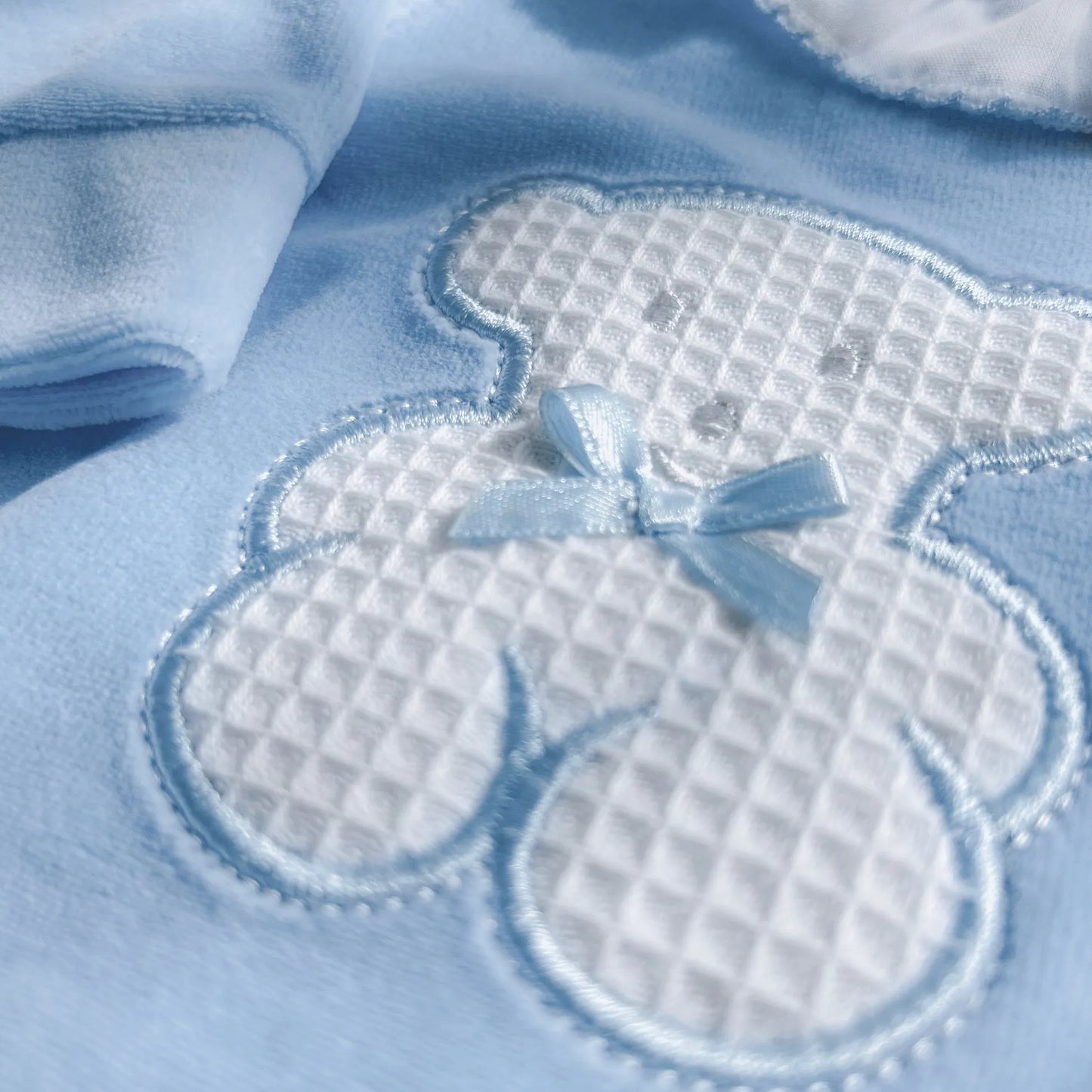 Detalle de pelele con cuello de volante y motivo de osito waffle azul