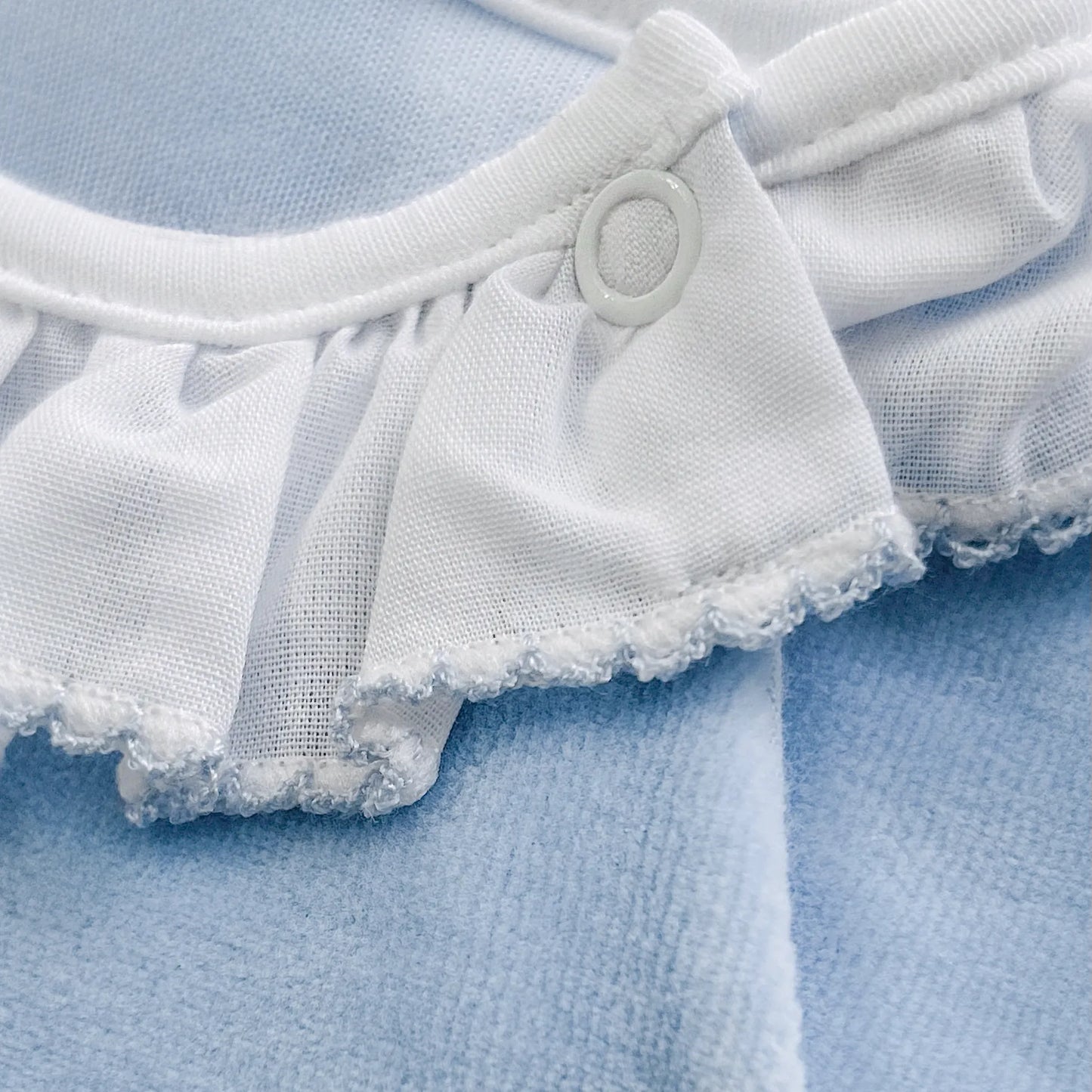 Detalle de pelele con cuello de volante y motivo de osito waffle azul