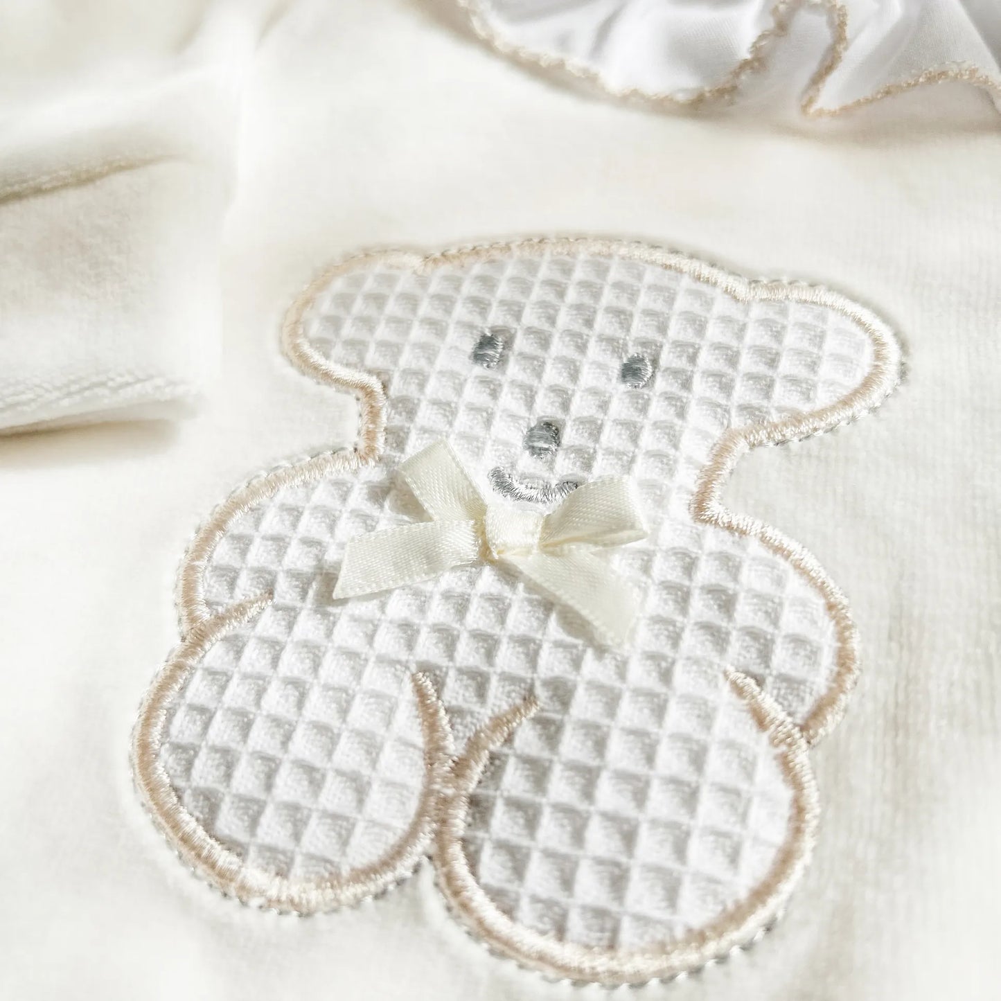 Detalle de pelele con cuello de volante y motivo de osito waffle perla