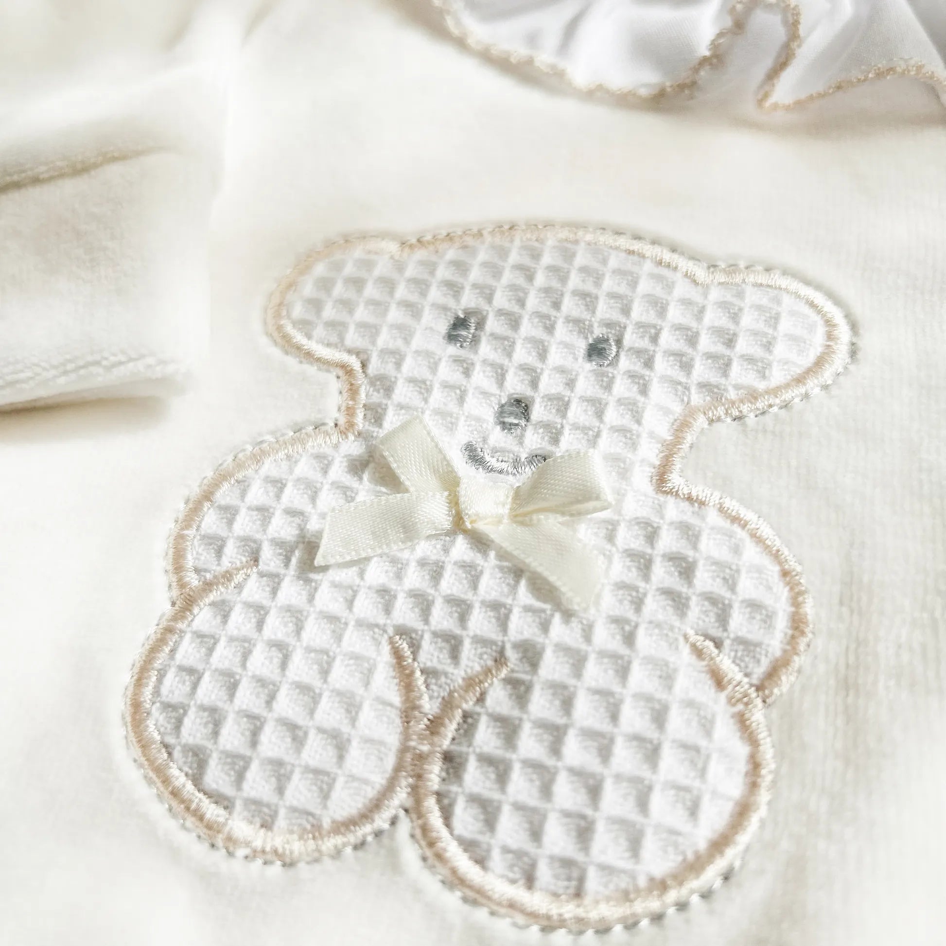 Detalle de pelele con cuello de volante y motivo de osito waffle perla