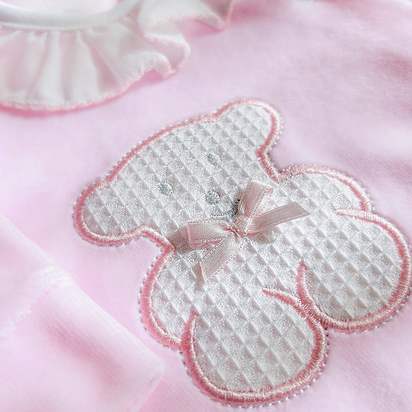 Detalle de pelele con cuello de volante y motivo de osito waffle rosa