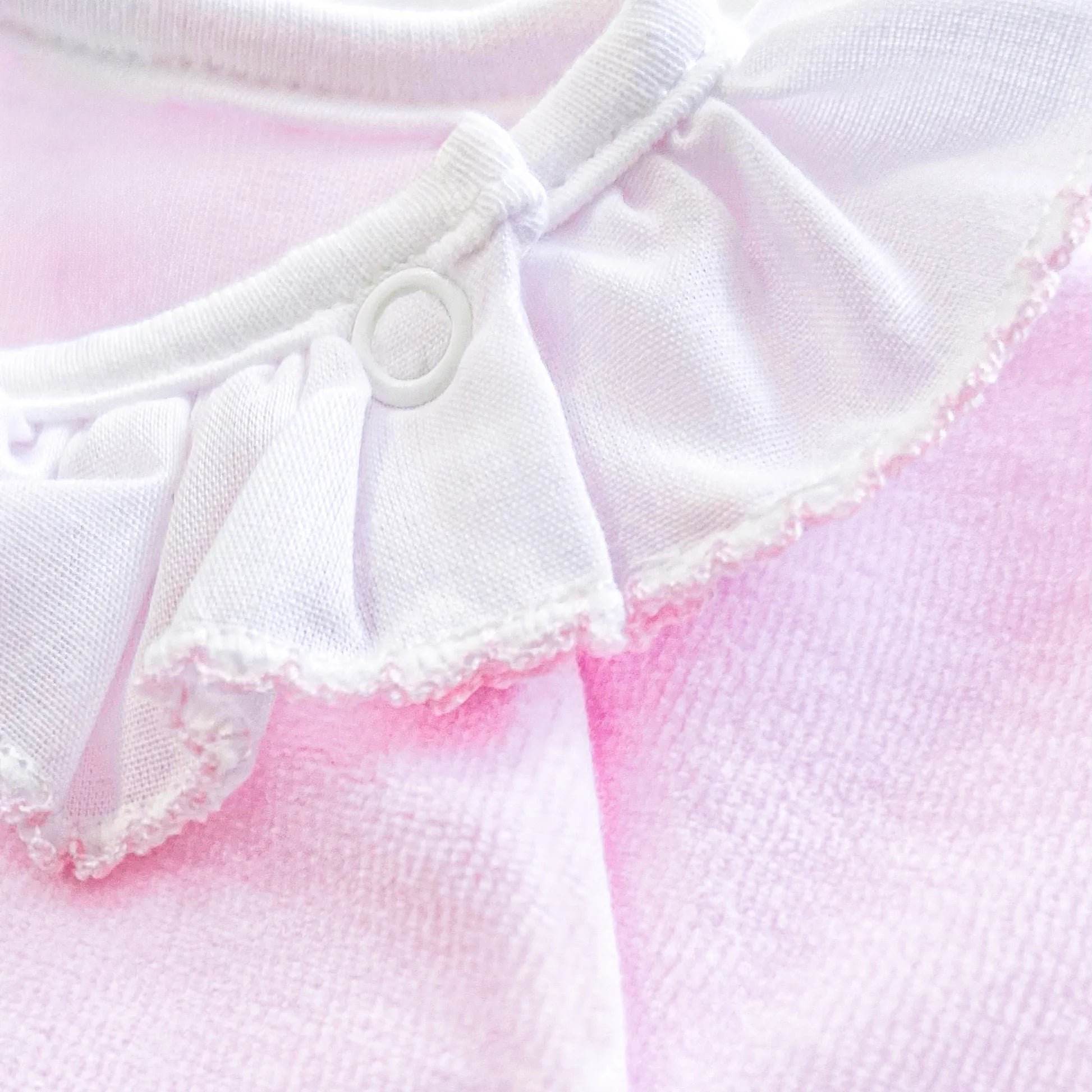 Detalle de pelele con cuello de volante y motivo de osito waffle rosa