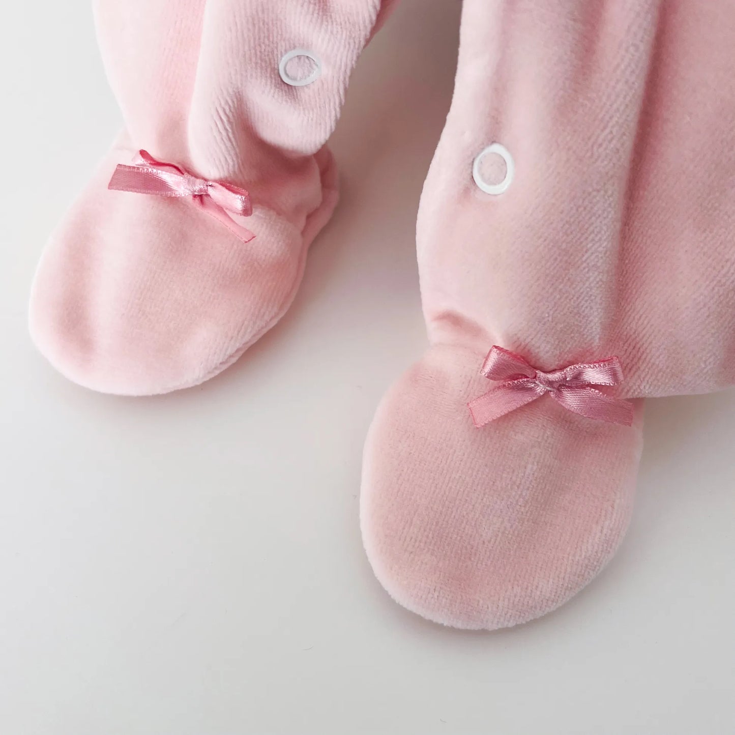 Detalle de pelele de niña con cuello redondo y bordado de rombos rosa
