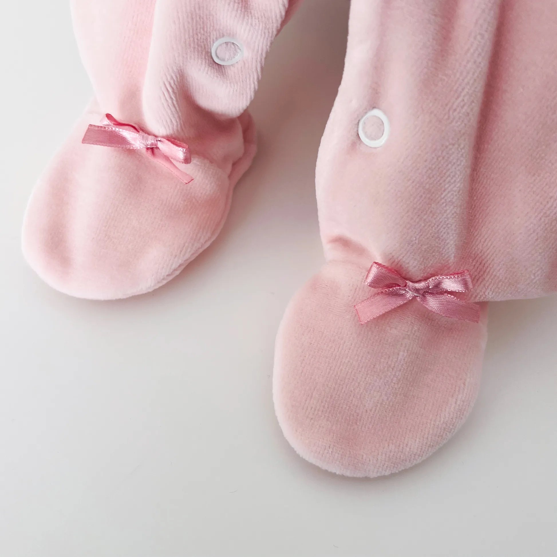 Detalle de pelele de niña con cuello redondo y bordado de rombos rosa