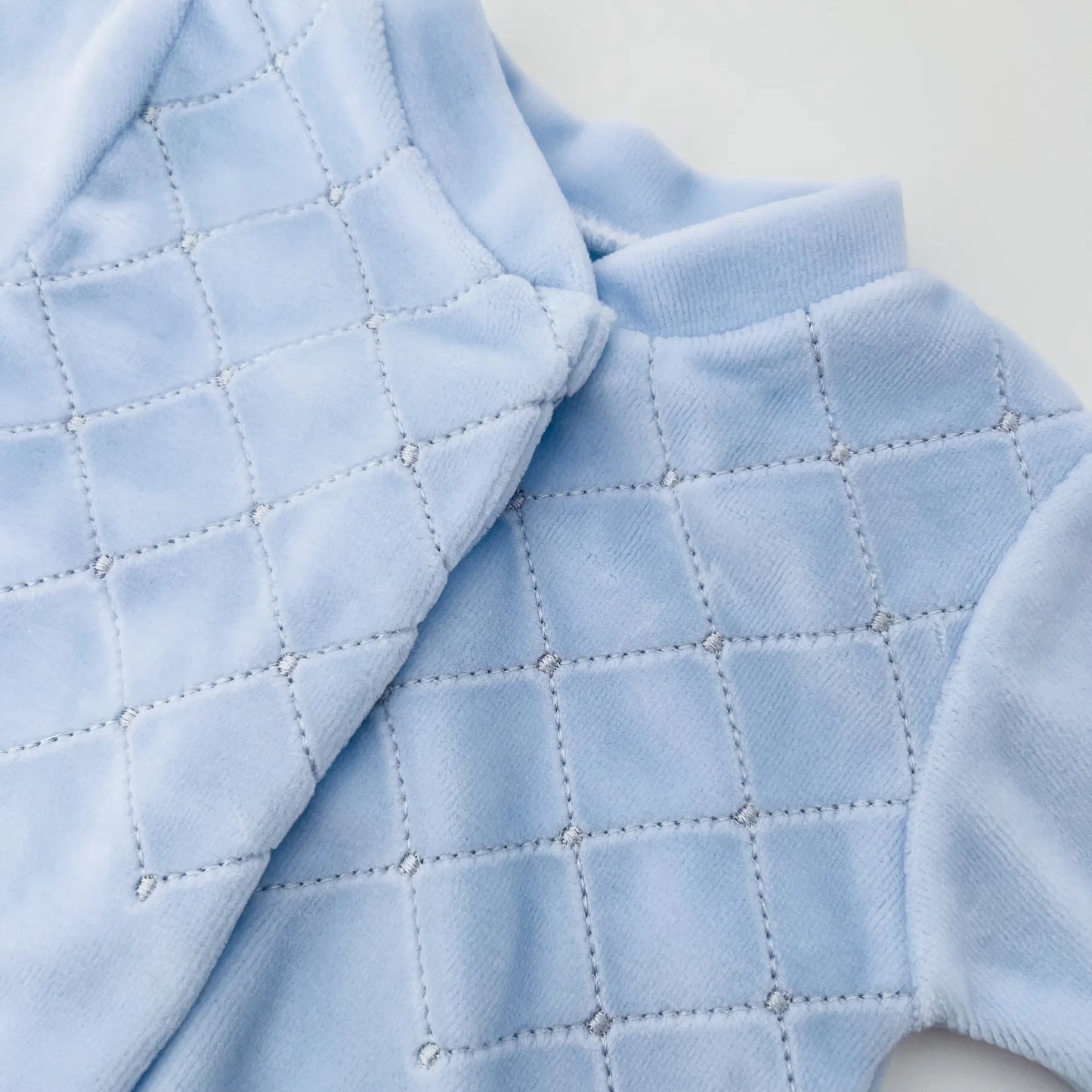 Detalle de pelele de niño con bordado de rombos azul