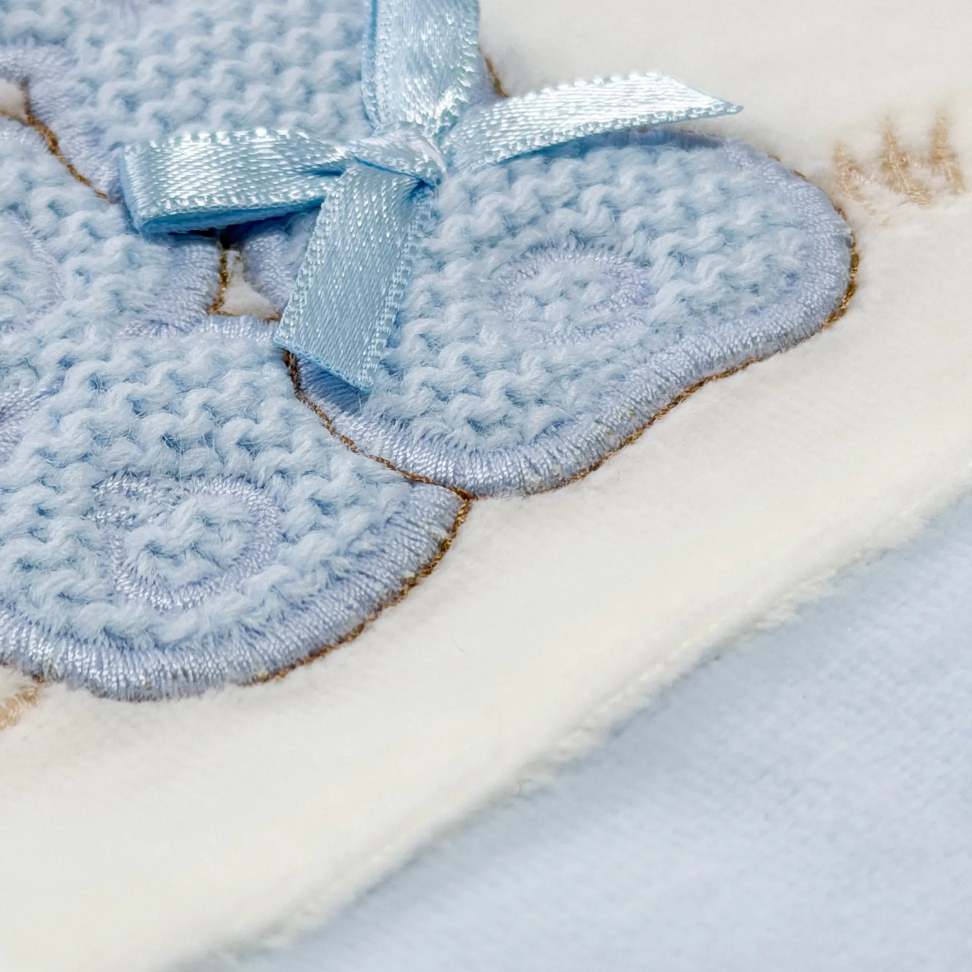 Detalle de pelele con motivo de conejos de punto y lazito azul