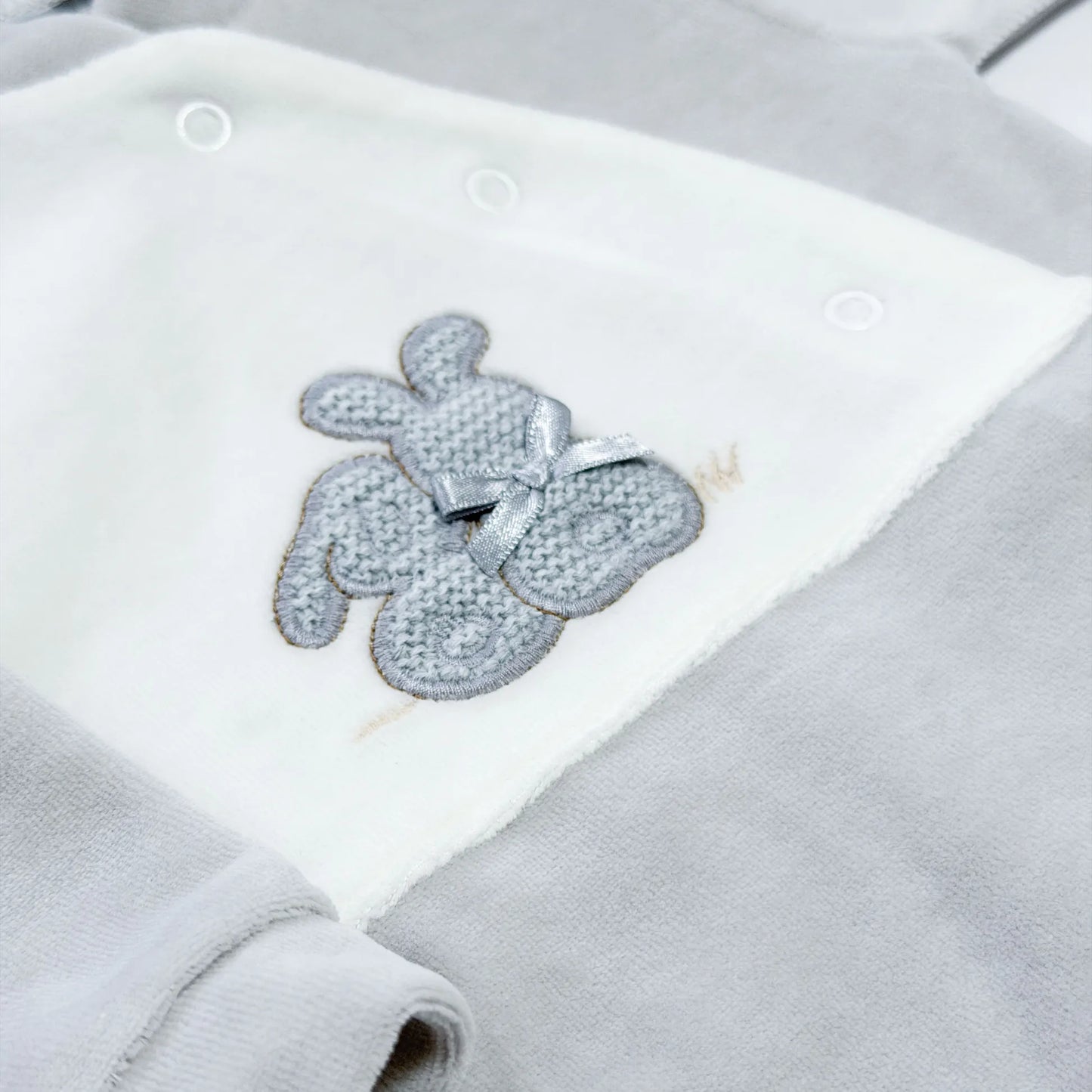Detalle de pelele con motivo de conejos de punto y lazito gris