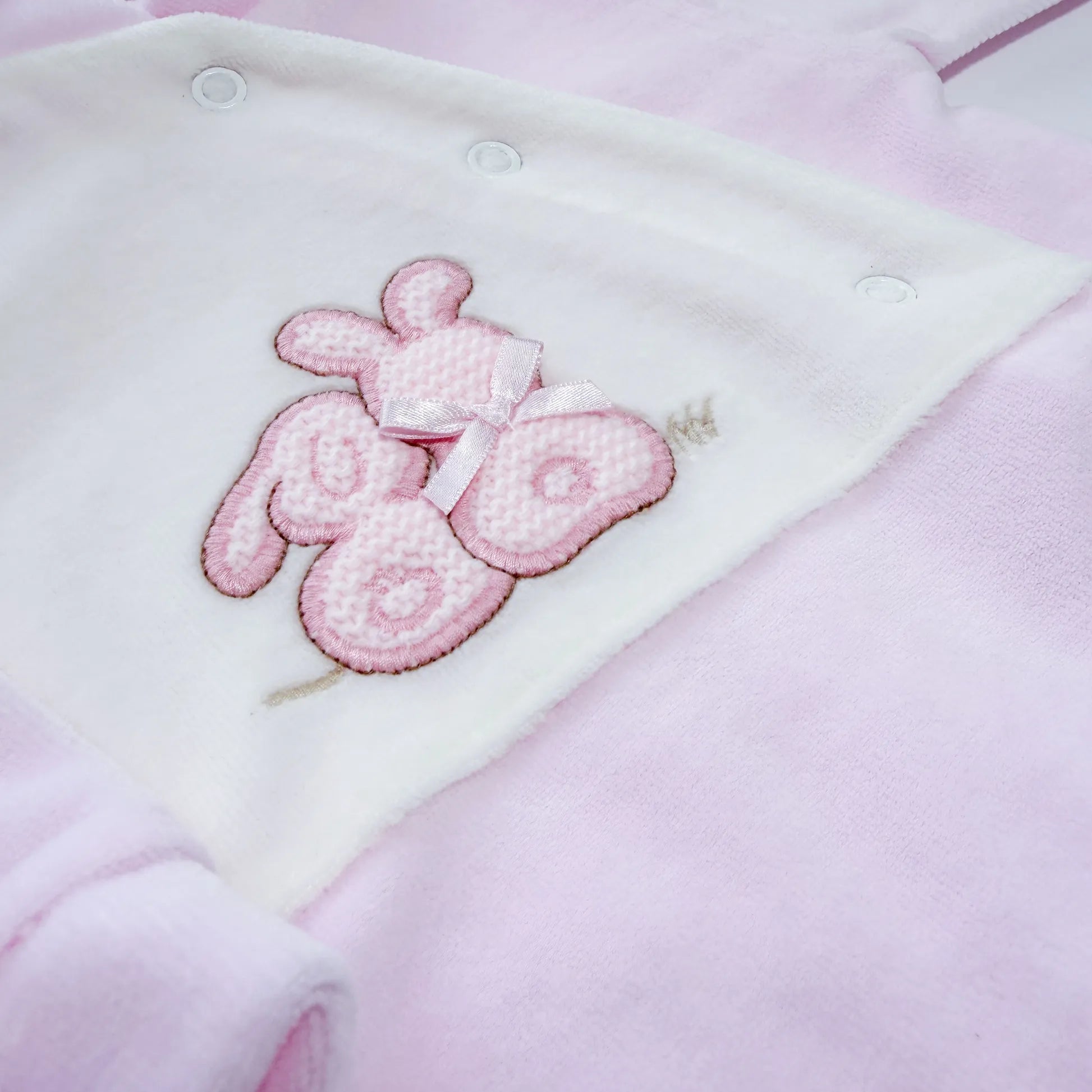 Detalle de pelele con motivo de conejos de punto y lazito rosa