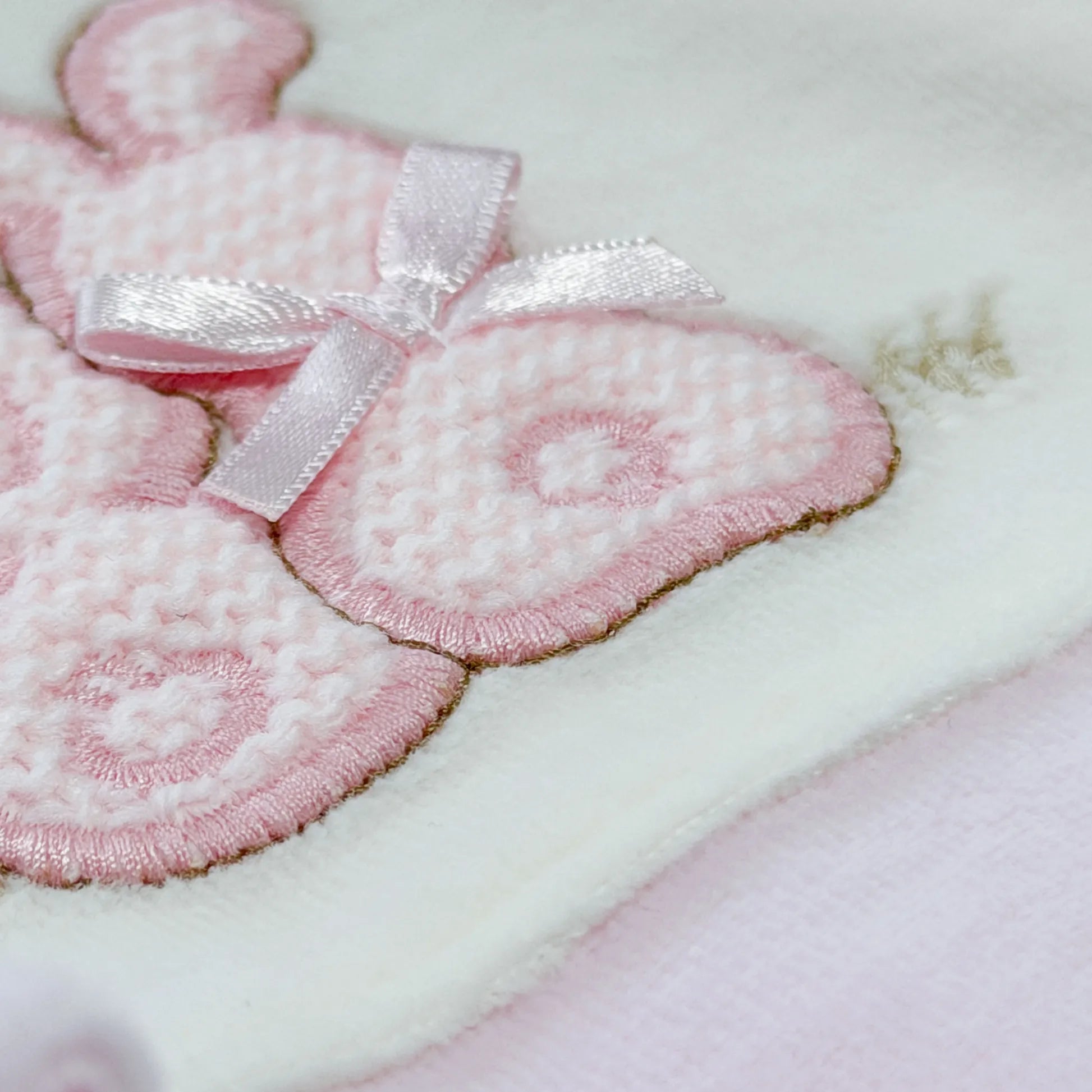 Detalle de pelele con motivo de conejos de punto y lazito rosa