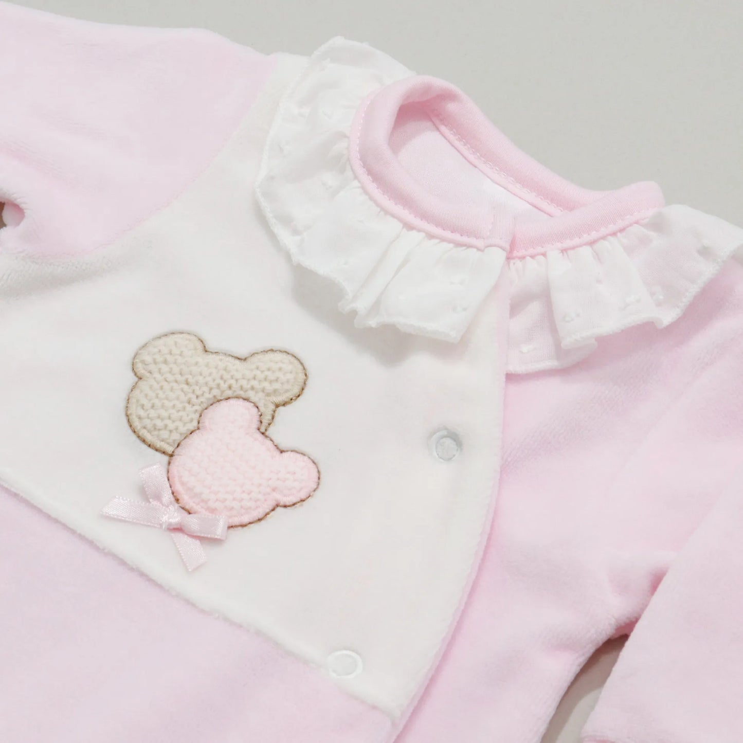 Detalle de pelele con motivo de ositos de punto y lazito rosa