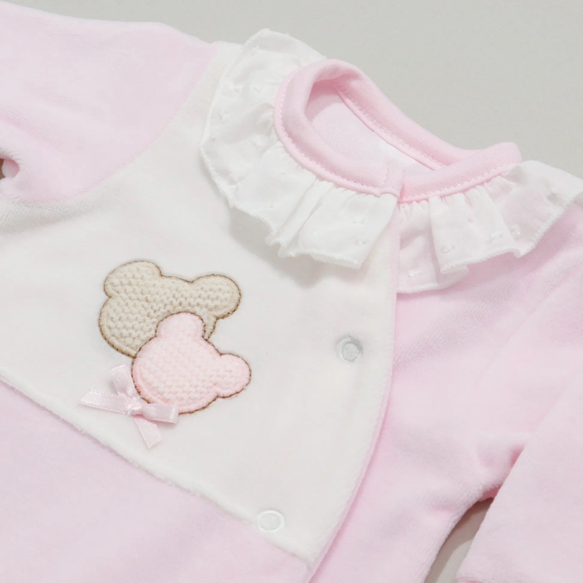 Detalle de pelele con motivo de ositos de punto y lazito rosa