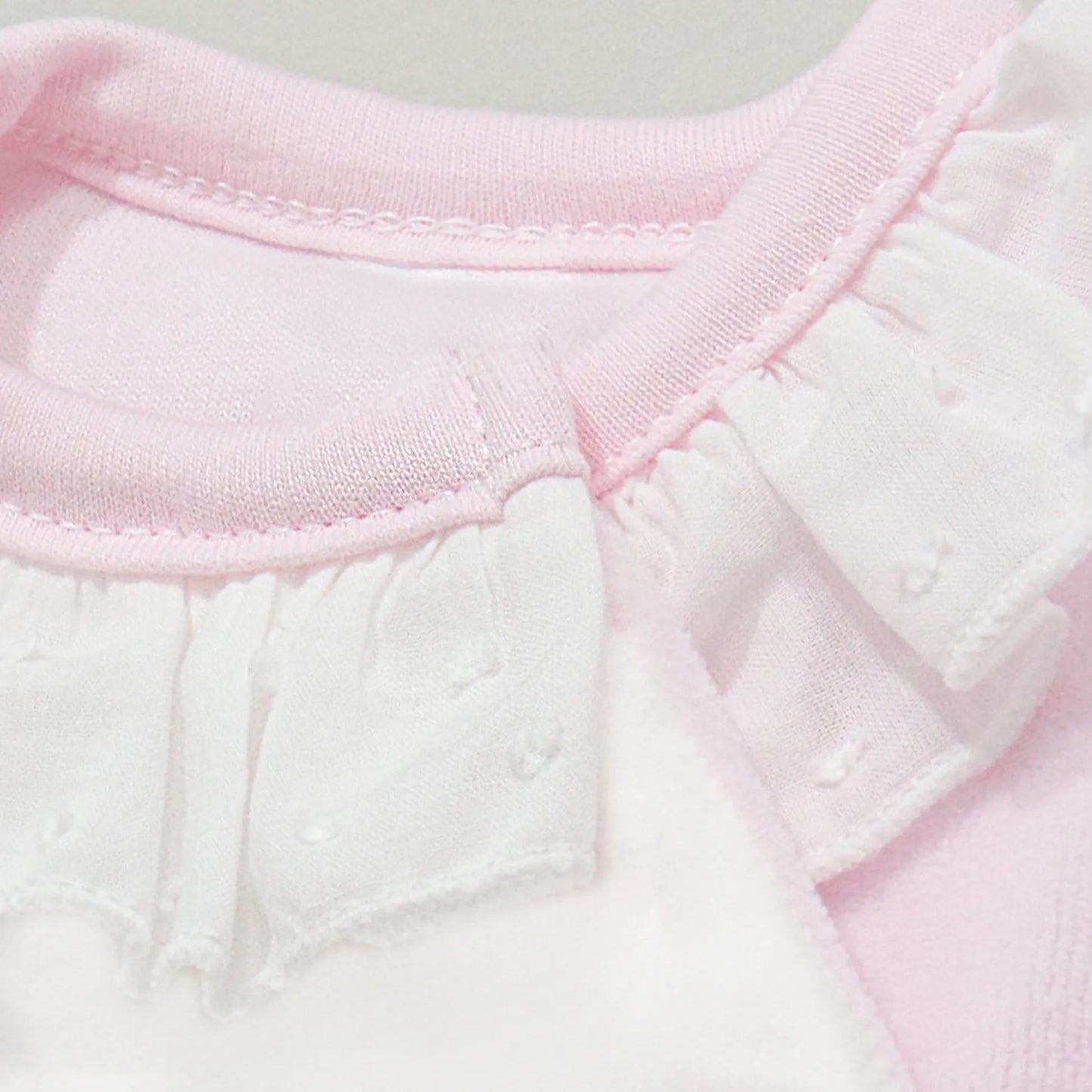 Detalle de pelele con motivo de ositos de punto y lazito rosa