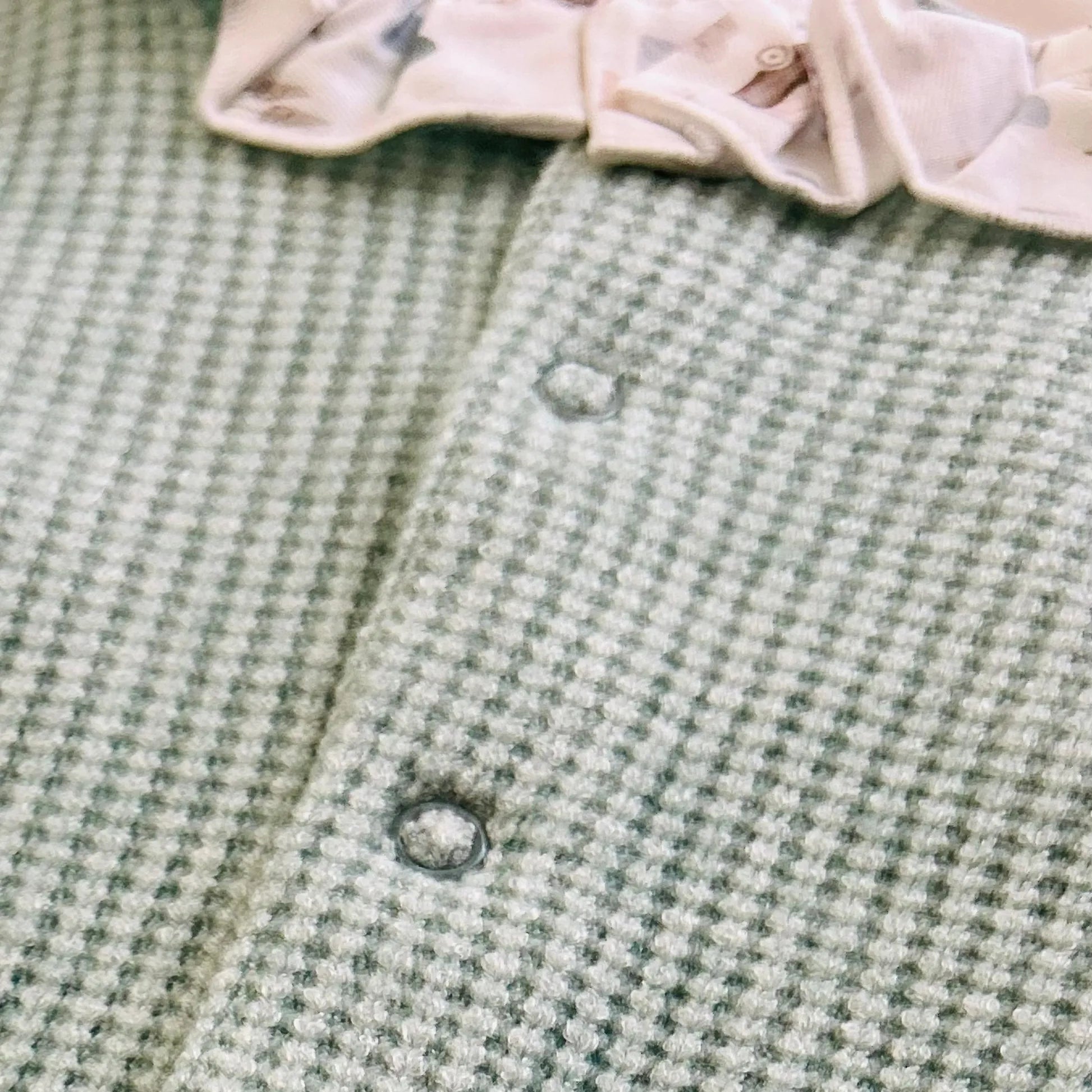 Detalle de pelele de punto con volante en el cuello y pechera en contraste verde