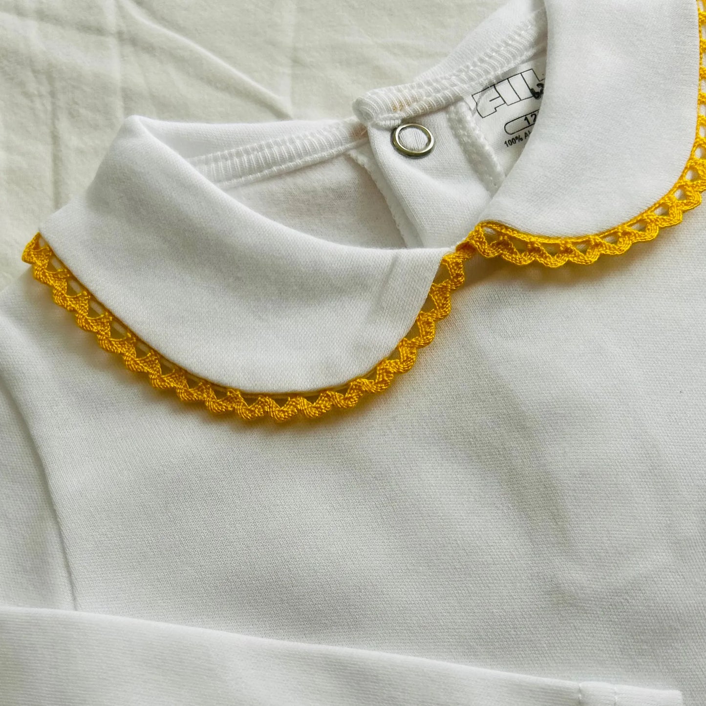 Detalle de body de manga larga perchado con aplicación bordada de color alrededor del cuello amarillo