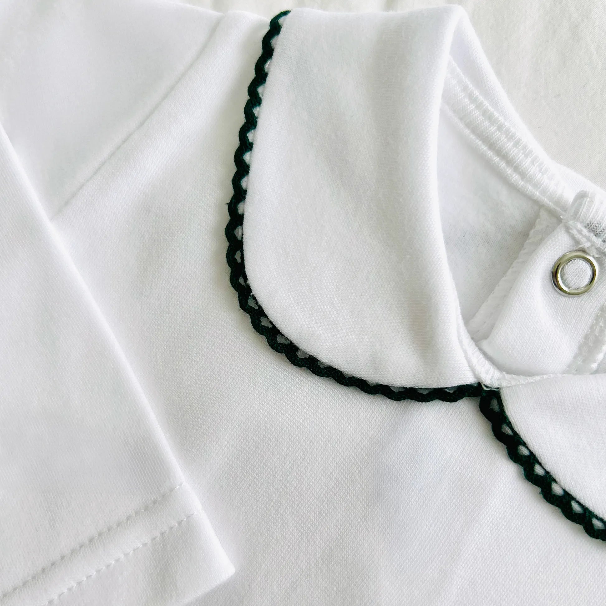 Detalle de body de manga larga perchado con aplicación bordada de color alrededor del cuello verde