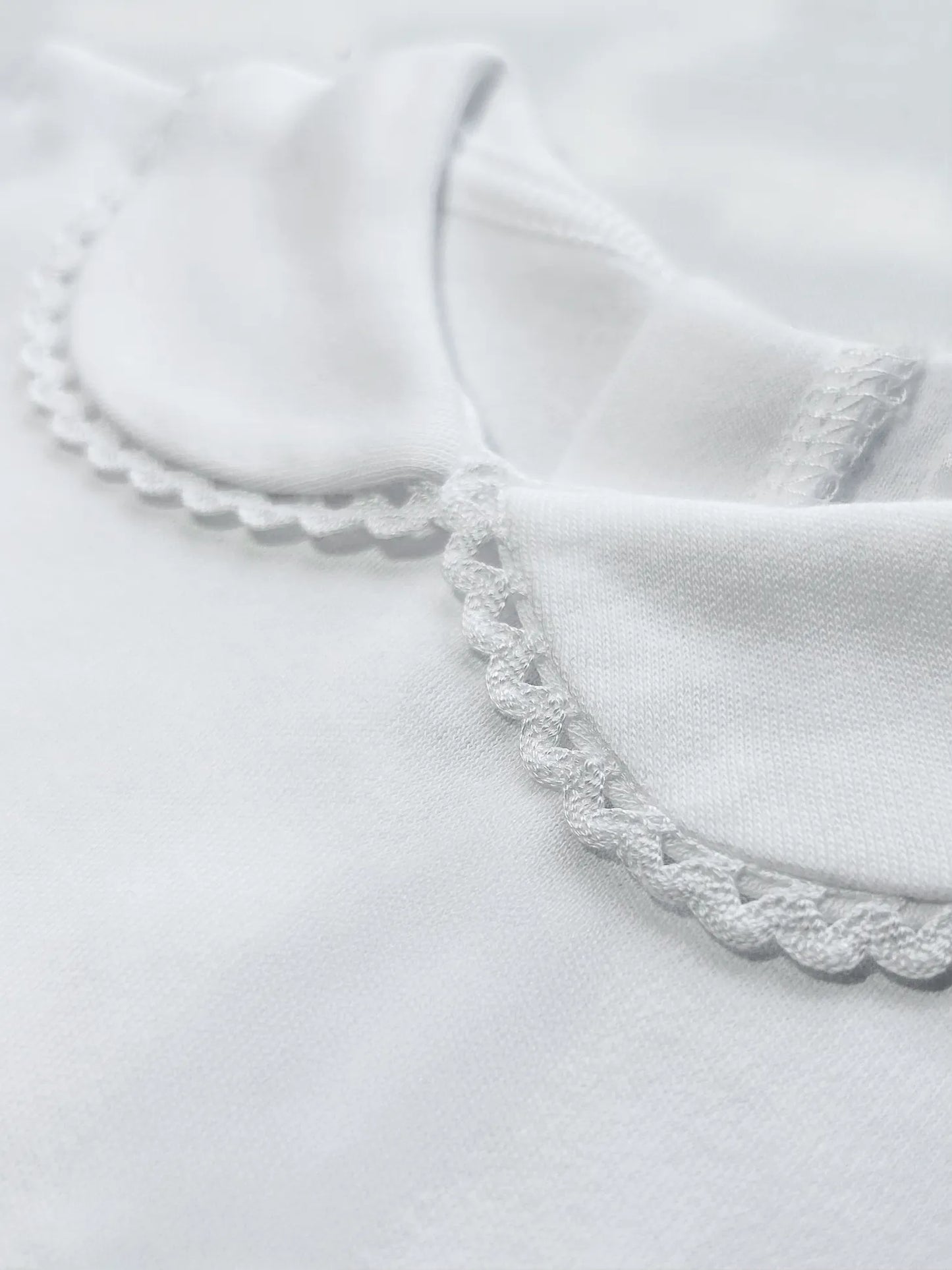 Detalle de body de manga larga perchado con aplicación bordada alrededor del cuello blanco