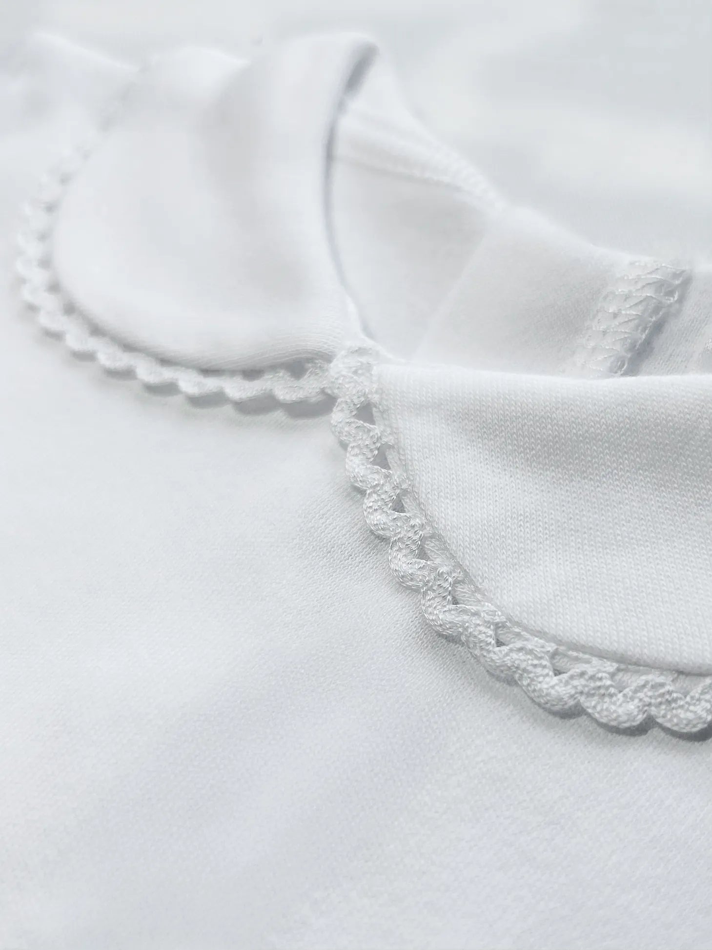 Detalle de body de manga larga perchado con aplicación bordada alrededor del cuello blanco