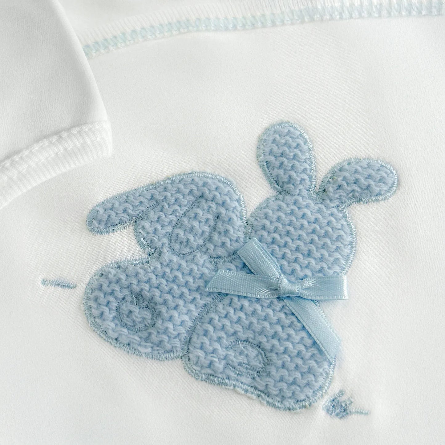 Detalle de body cruzado con leotardo perchado con motivo de conejos de punto y lazito azul