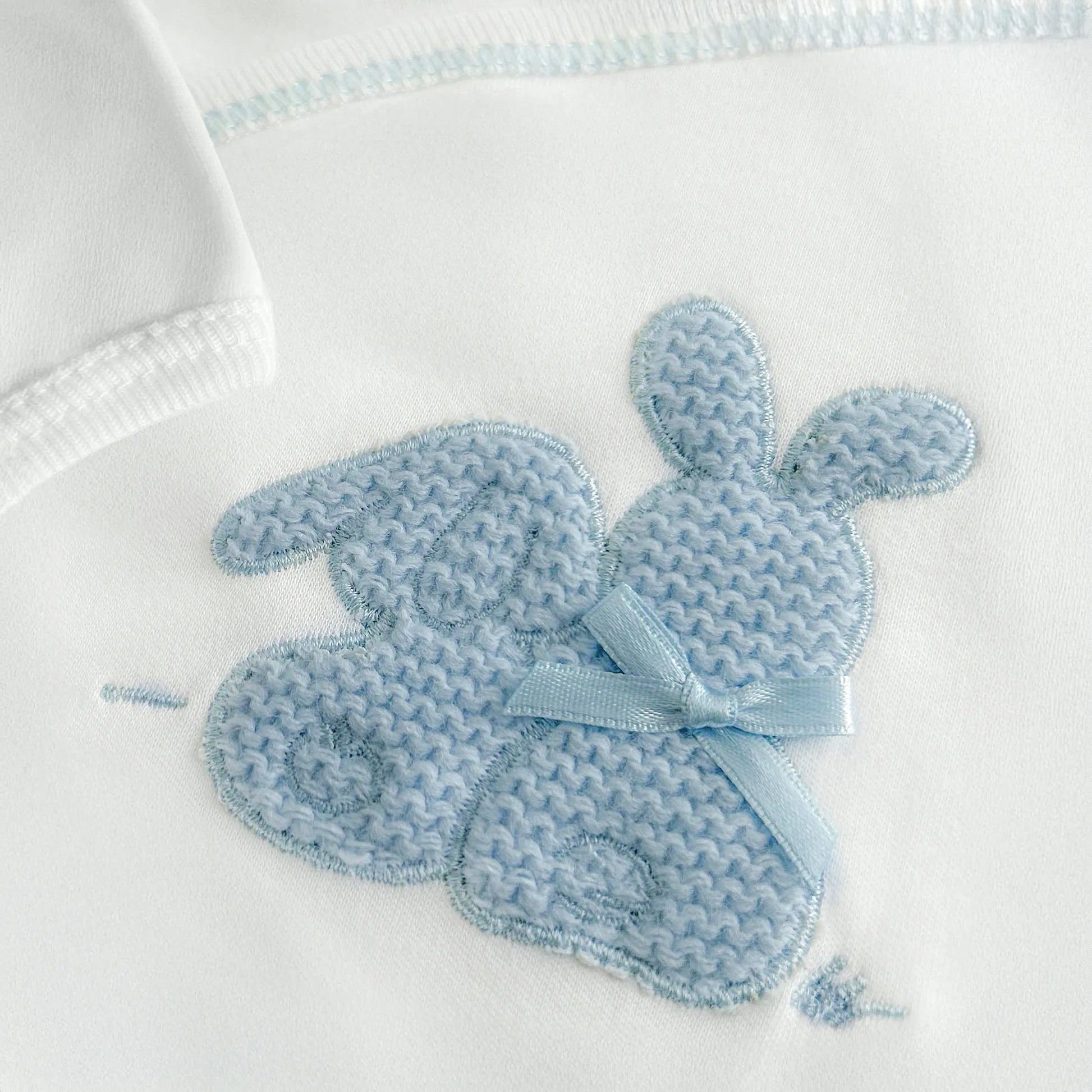 Detalle de body cruzado con leotardo perchado con motivo de conejos de punto y lazito azul