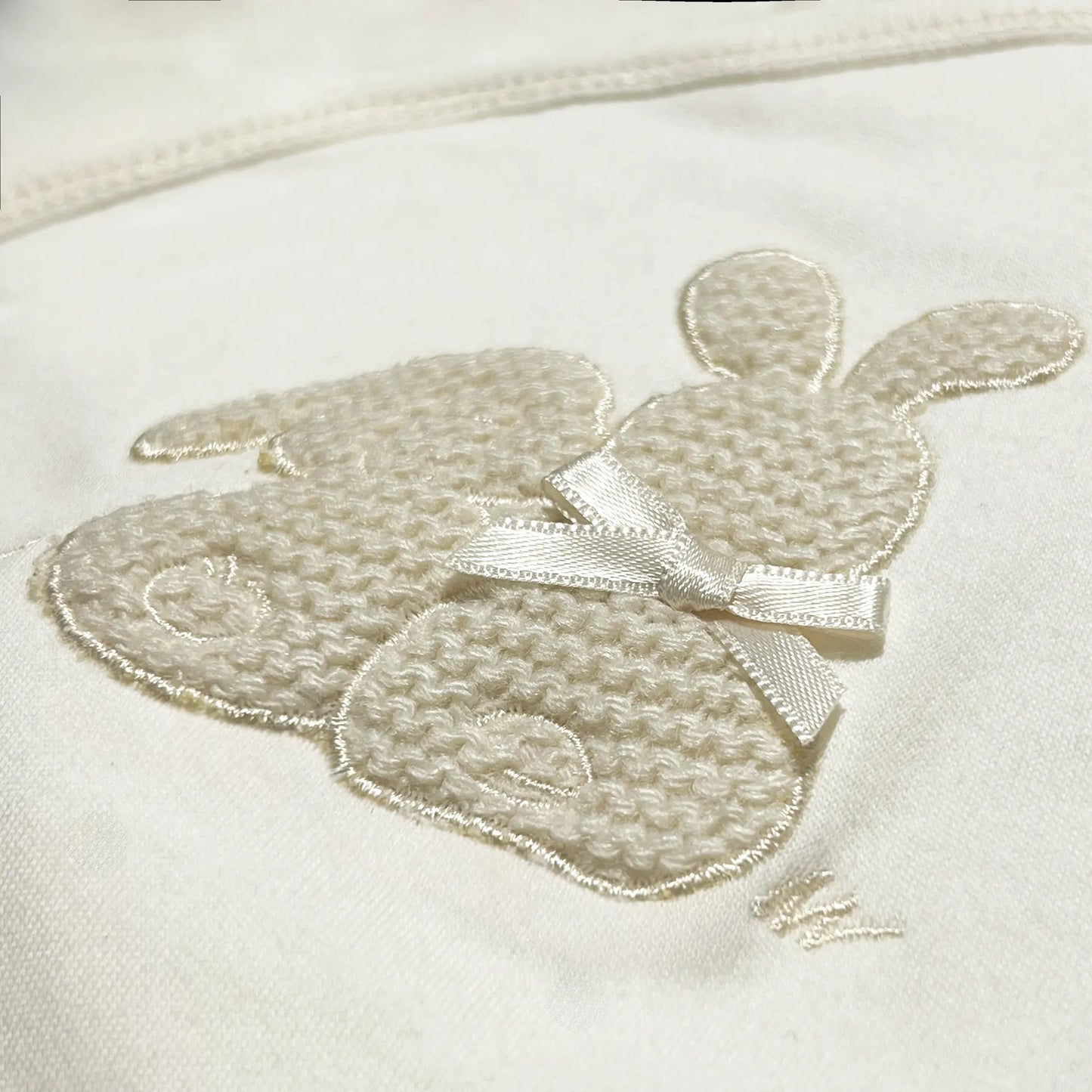 Detalle de body cruzado con leotardo perchado con motivo de conejos de punto y lazito beige