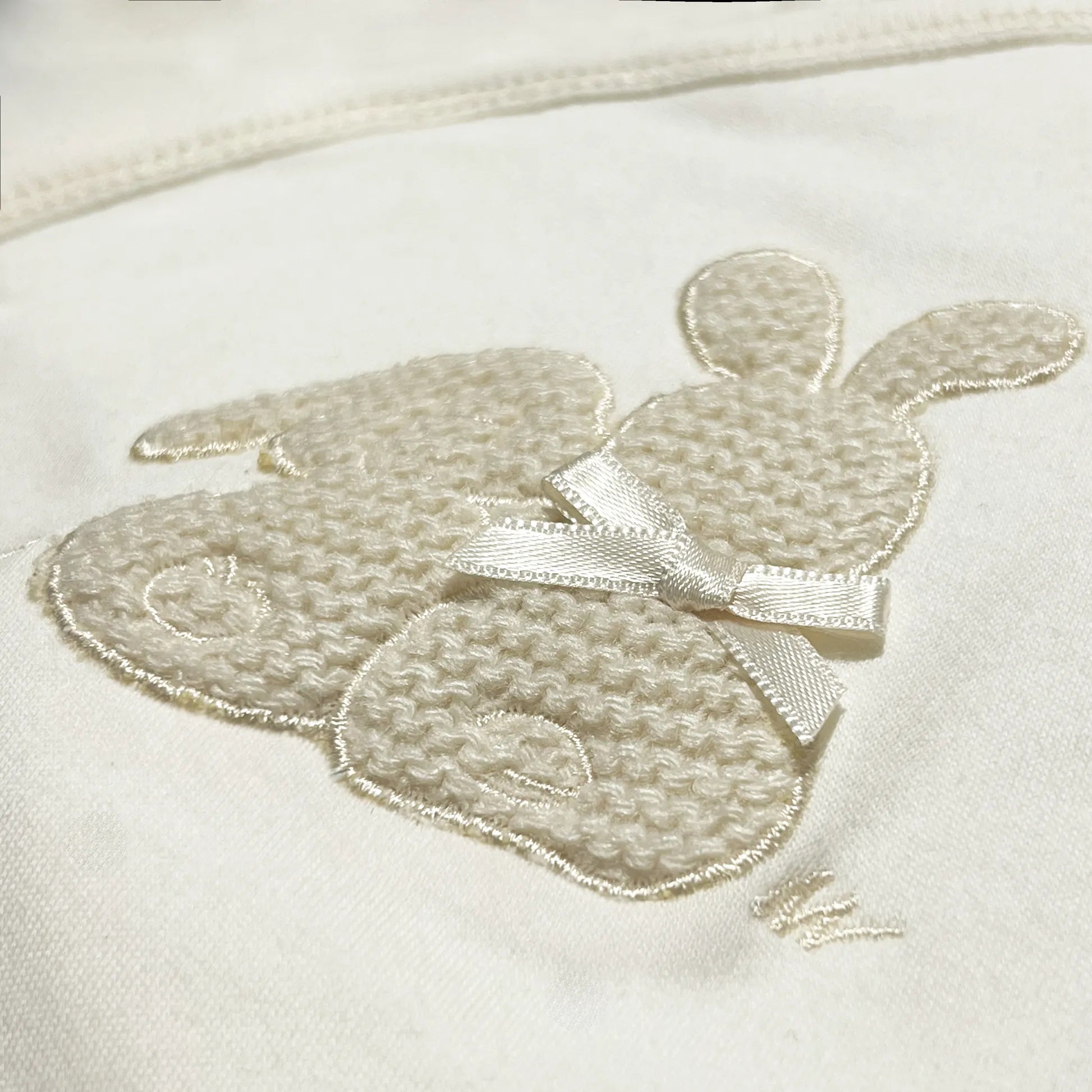 Detalle de body cruzado con leotardo perchado con motivo de conejos de punto y lazito beige