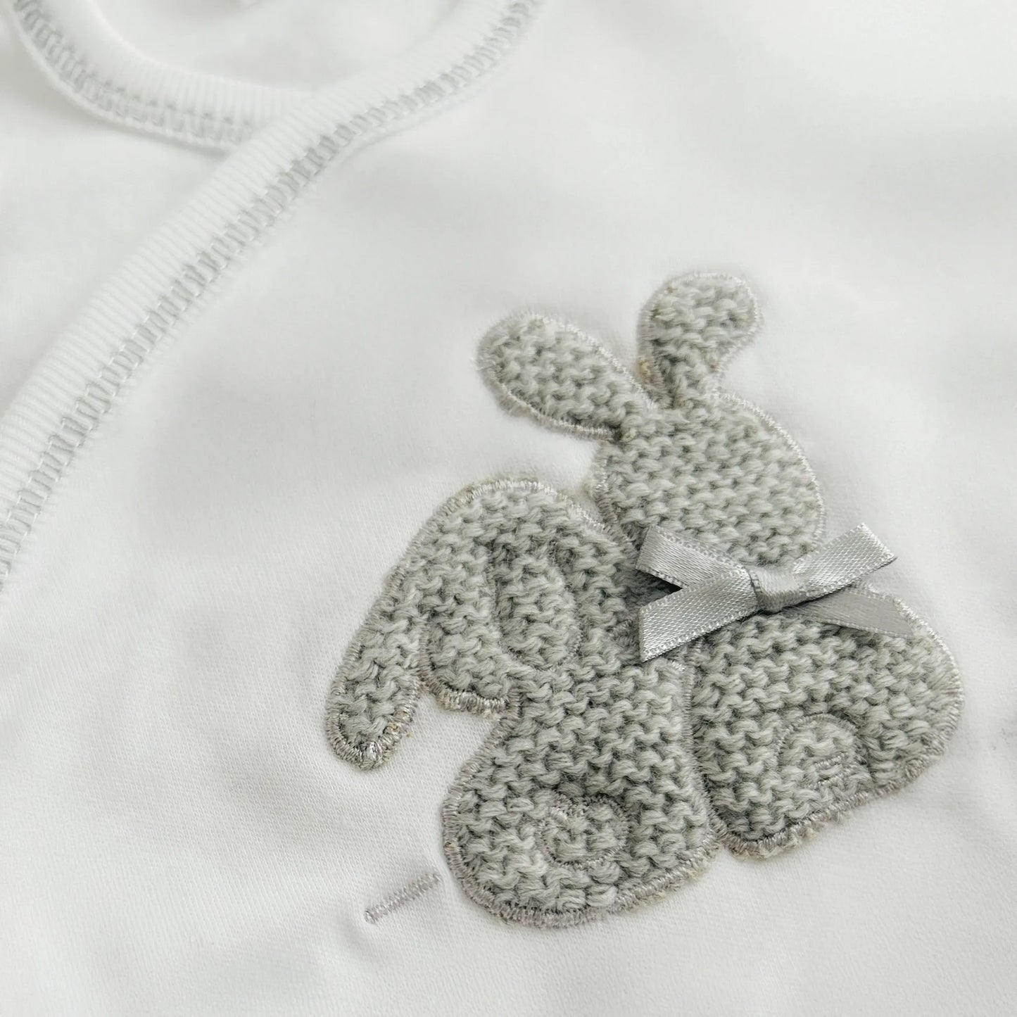 Detalle de body cruzado con leotardo perchado con motivo de conejos de punto y lazito gris