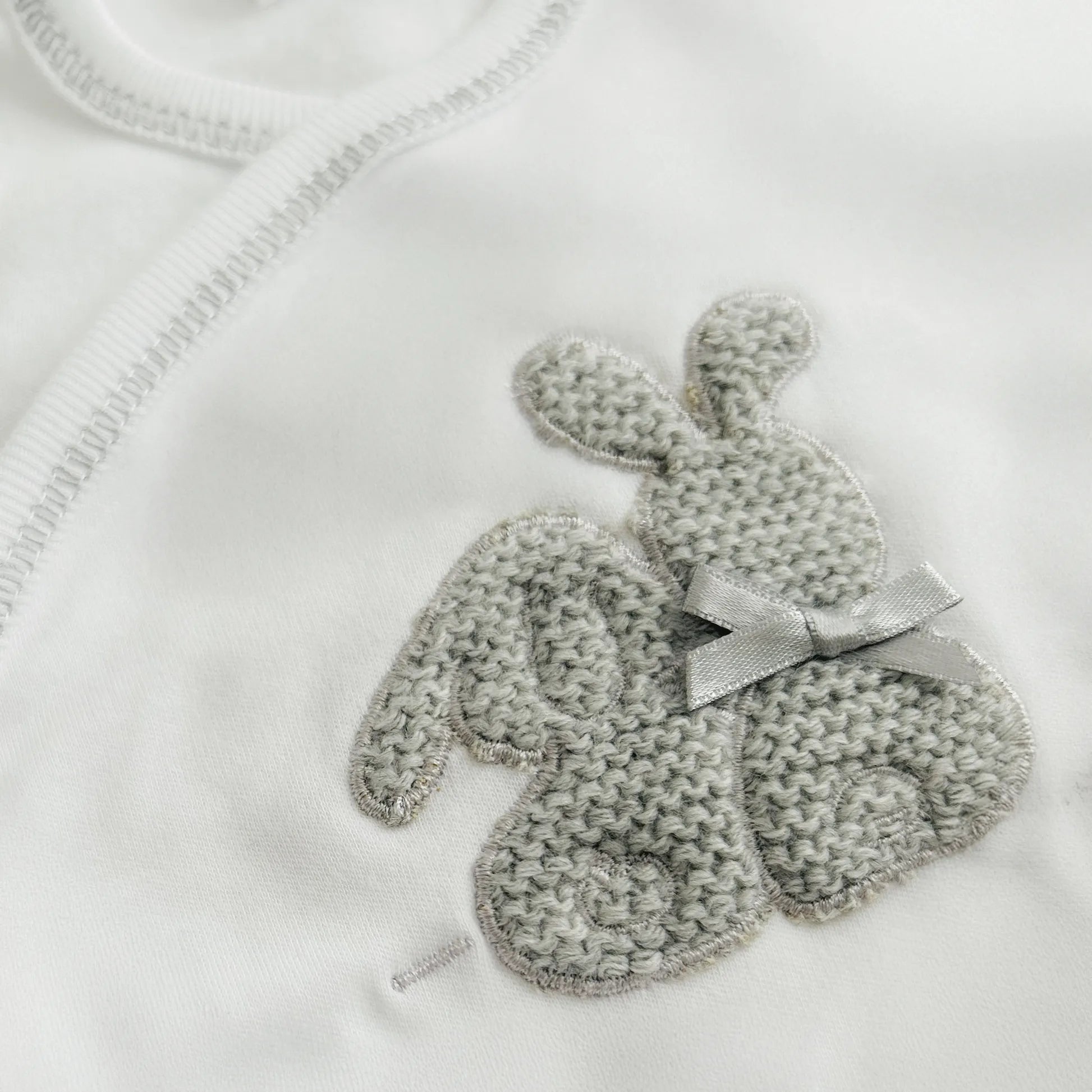 Detalle de body cruzado con leotardo perchado con motivo de conejos de punto y lazito gris