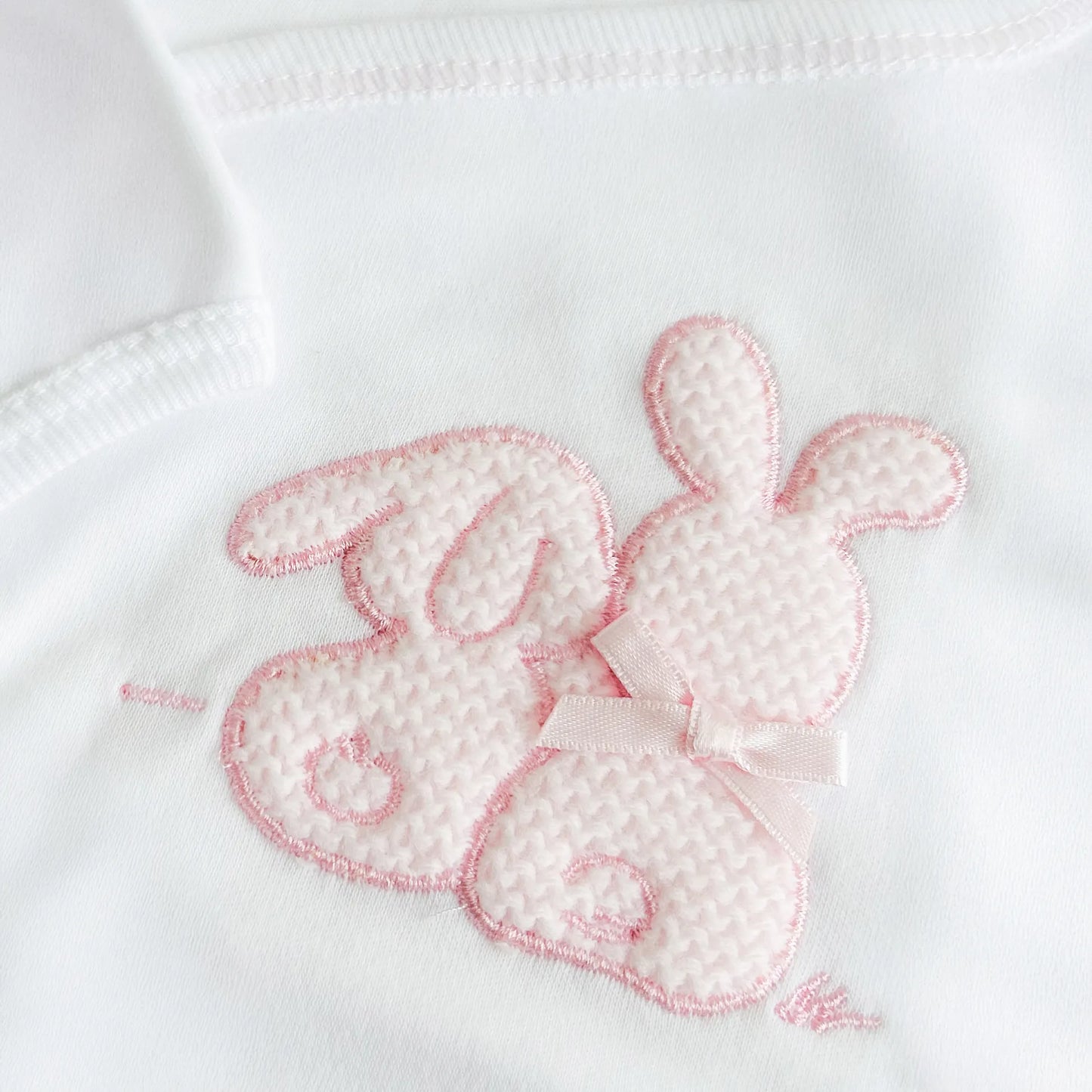 Detalle de body cruzado con leotardo perchado con motivo de conejos de punto y lazito rosa