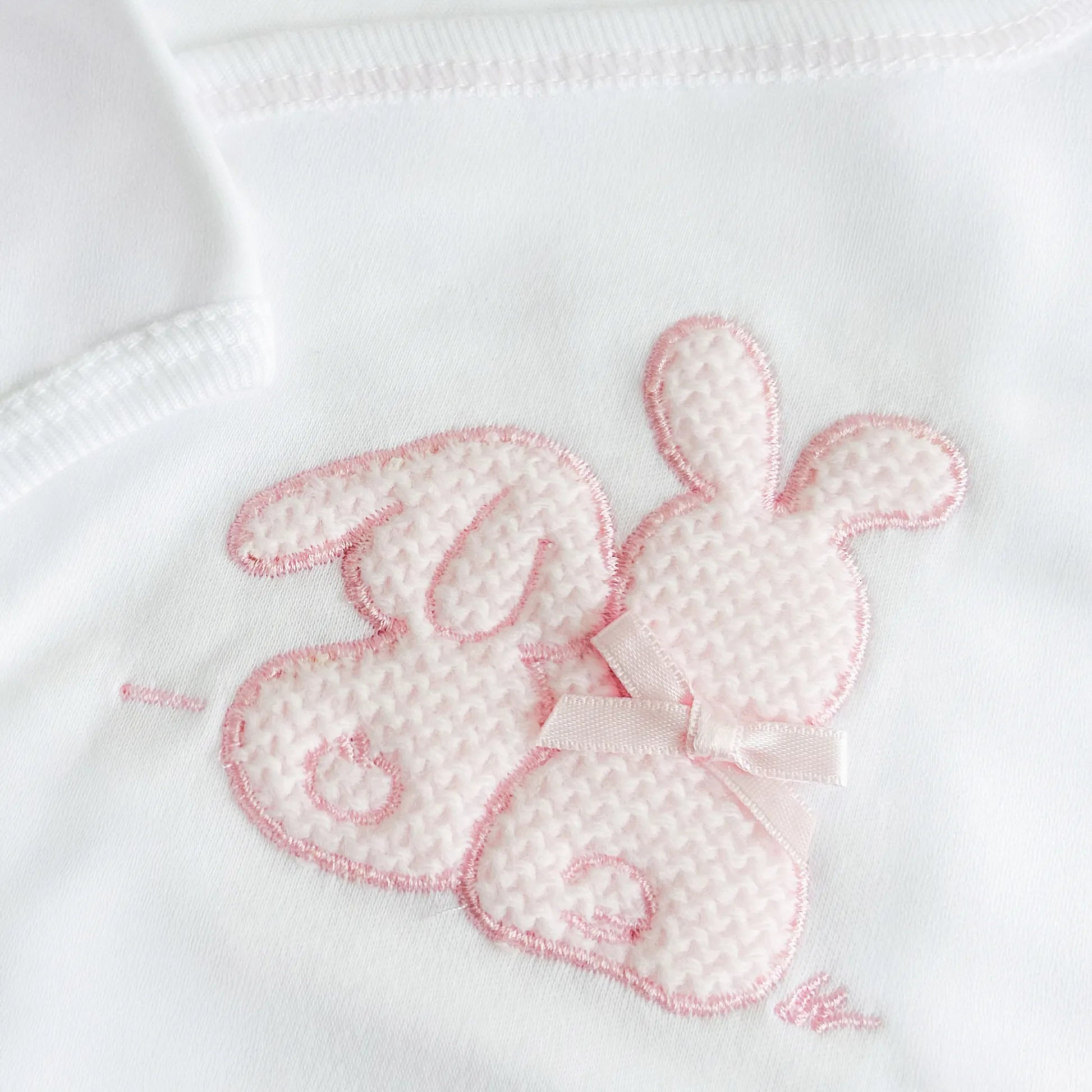 Detalle de body cruzado con leotardo perchado con motivo de conejos de punto y lazito rosa