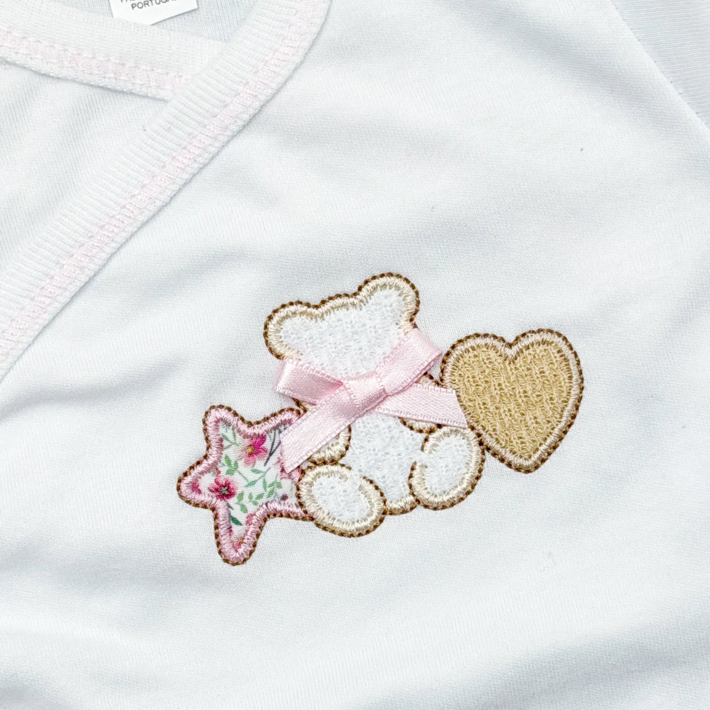 Detalle de body cruzado con polaina con motivo de osito entre estrella y corazón rosa