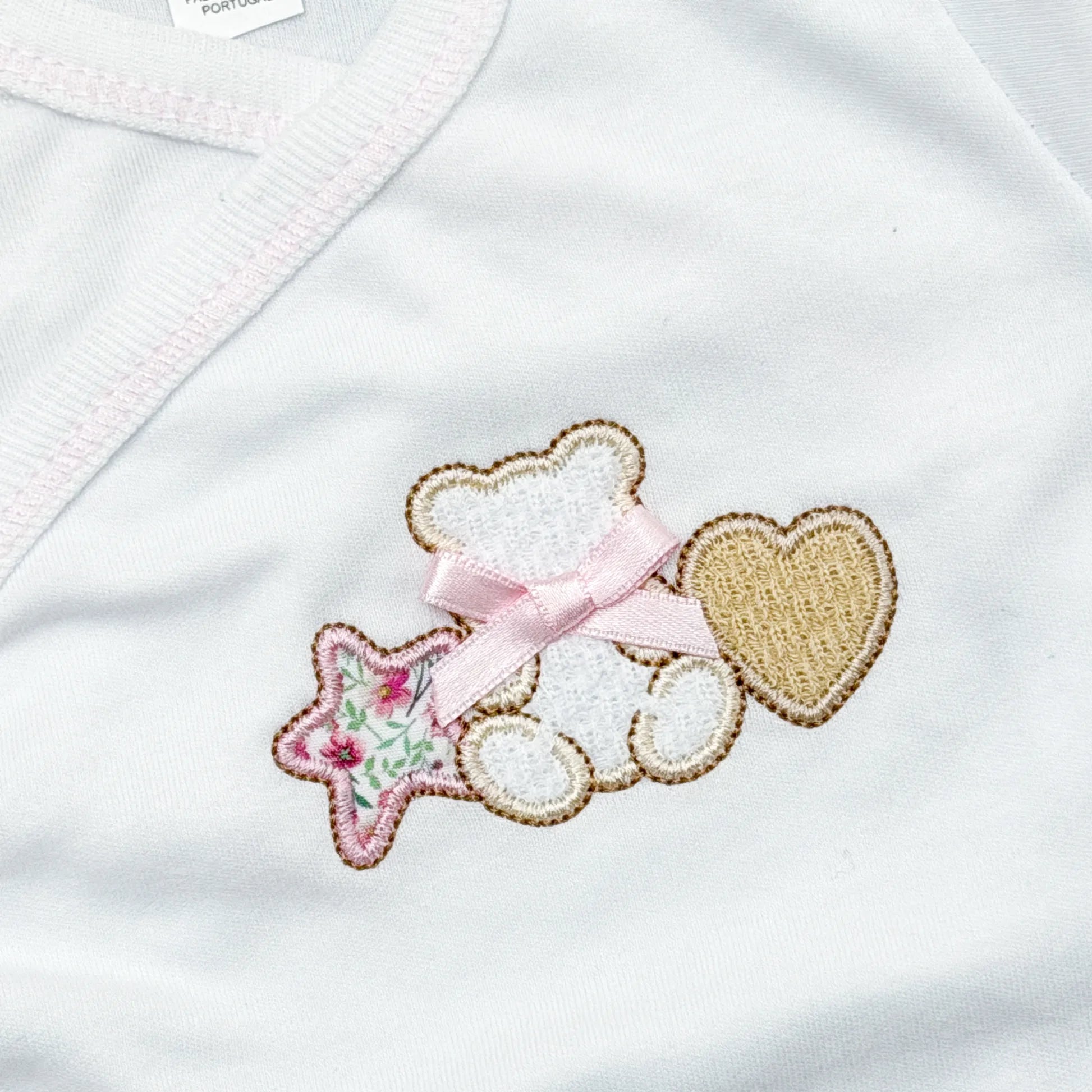 Detalle de body cruzado con polaina con motivo de osito entre estrella y corazón rosa