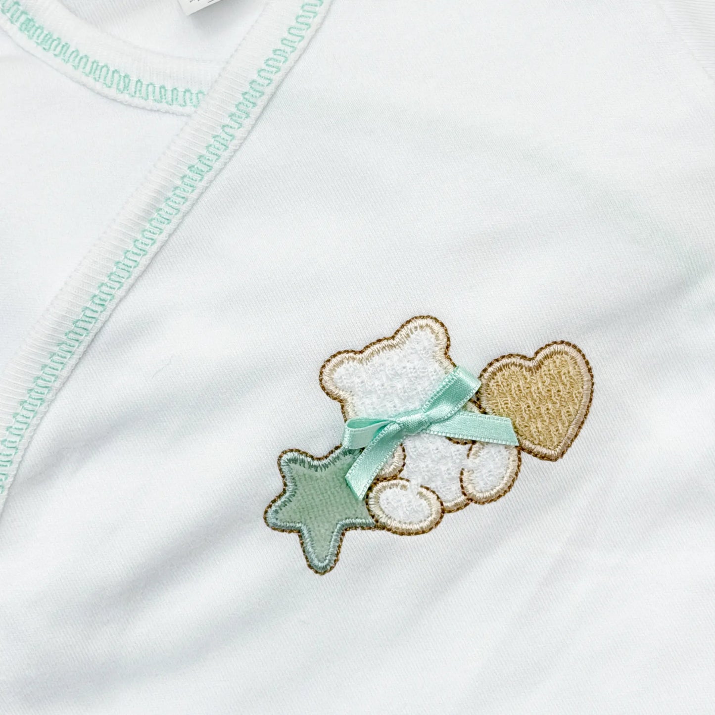Detalle de body cruzado con polaina con motivo de osito entre estrella y corazón verde