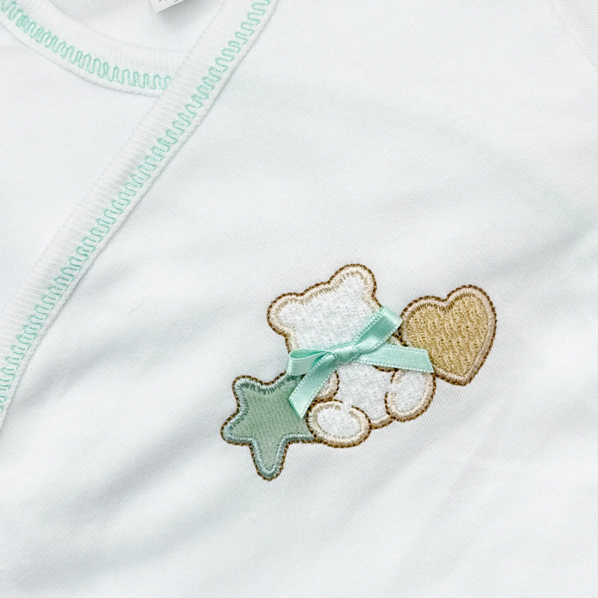Detalle de body cruzado con polaina con motivo de osito entre estrella y corazón verde
