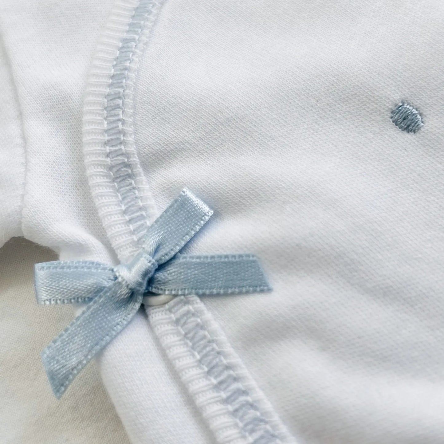 Detalle de body cruzado con pantalones com pies con bordado de lunares azul