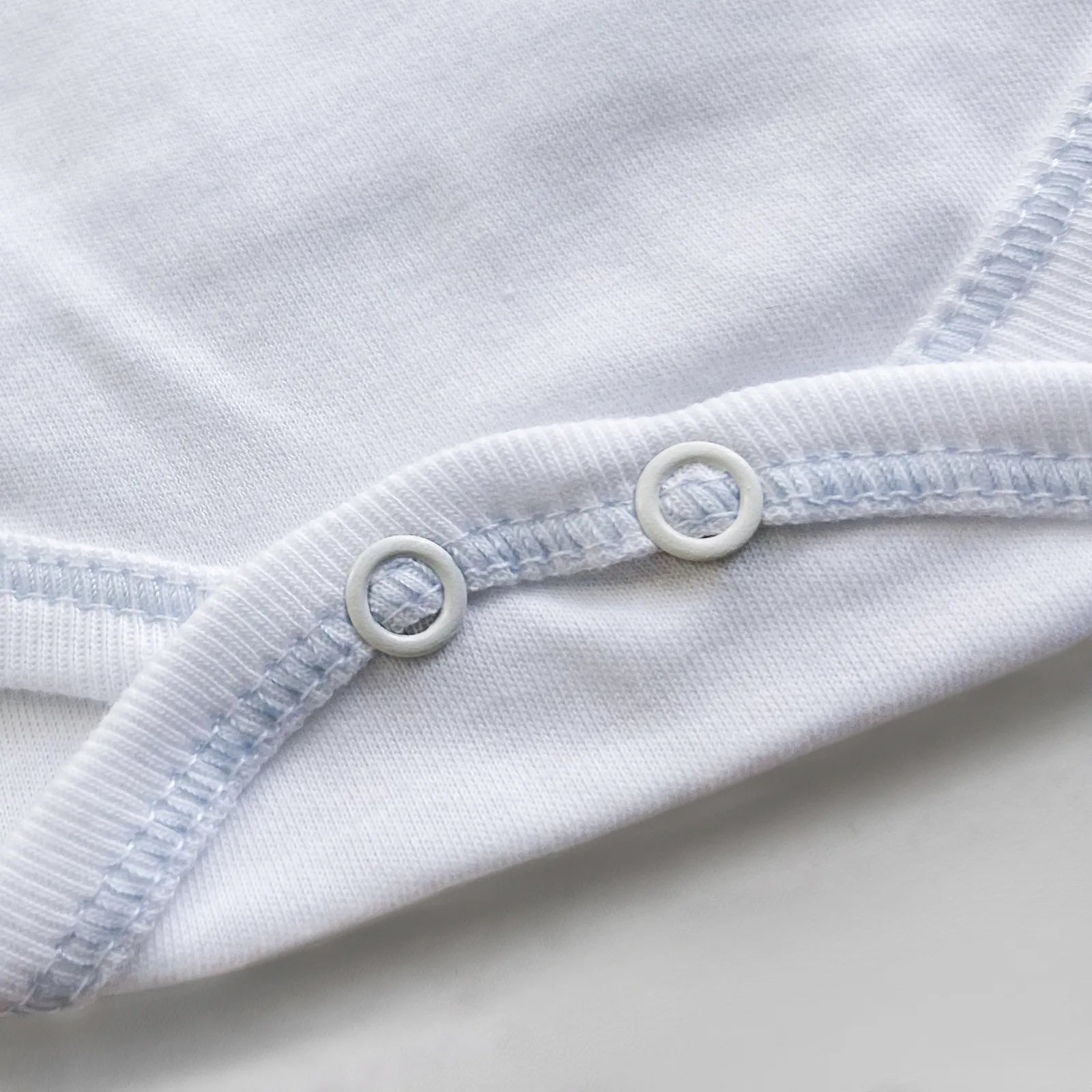 Detalle de body cruzado con pantalones com pies con bordado de lunares azul